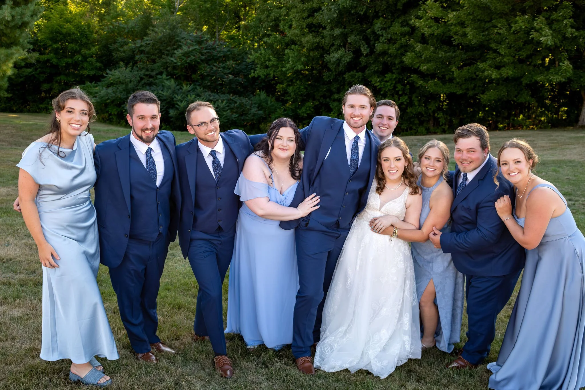 Zachary and Hollie with their full wedding party in navy and dusty blue in front of the trees at The Lucerne Inn in Dedham Maine summer wedding photography VMG Productions