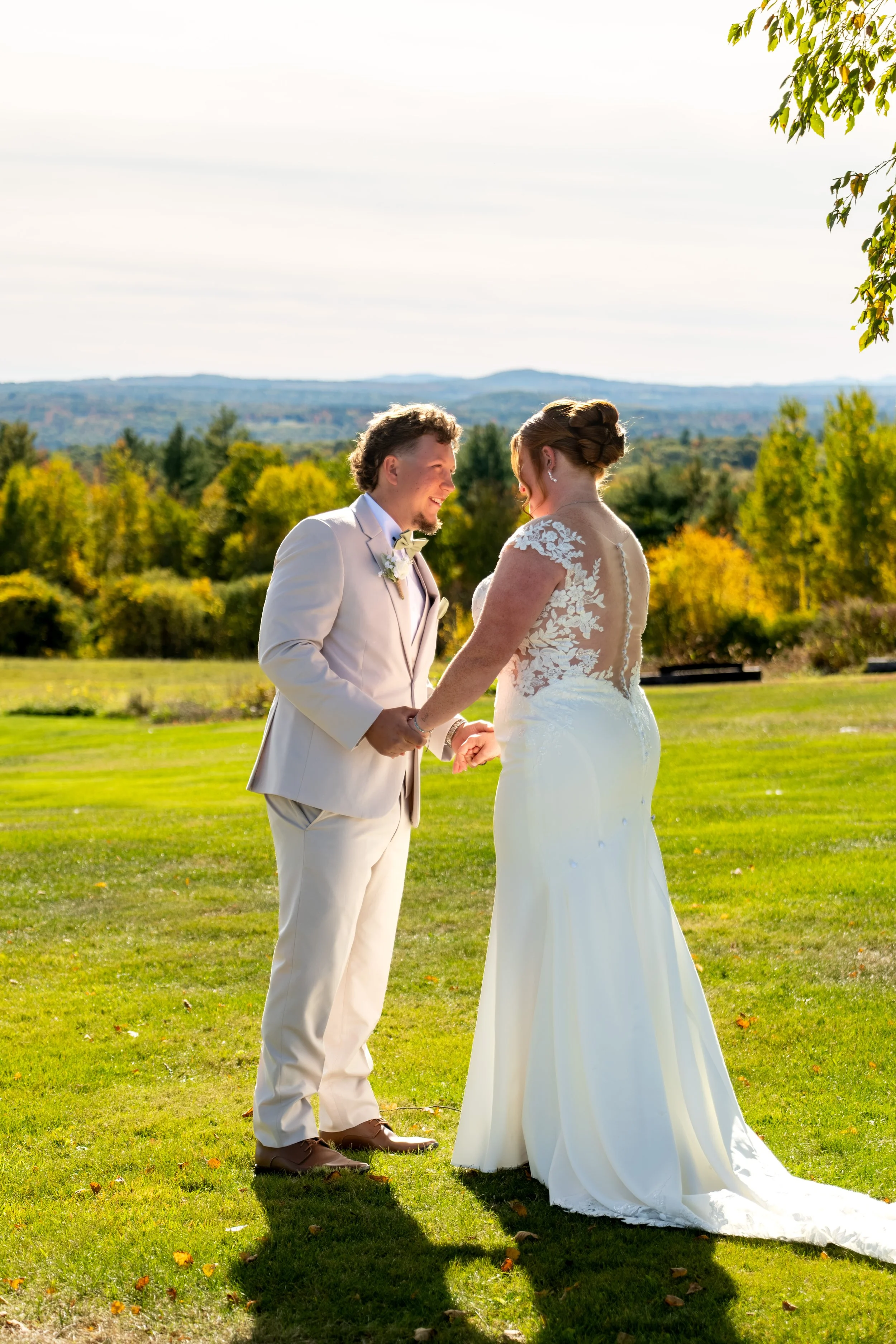 Andrew and Erika holding hands with the fall hills behind them at the Maine Wedding Barn and Event Center in Minot Maine fall wedding photography VMG Productions