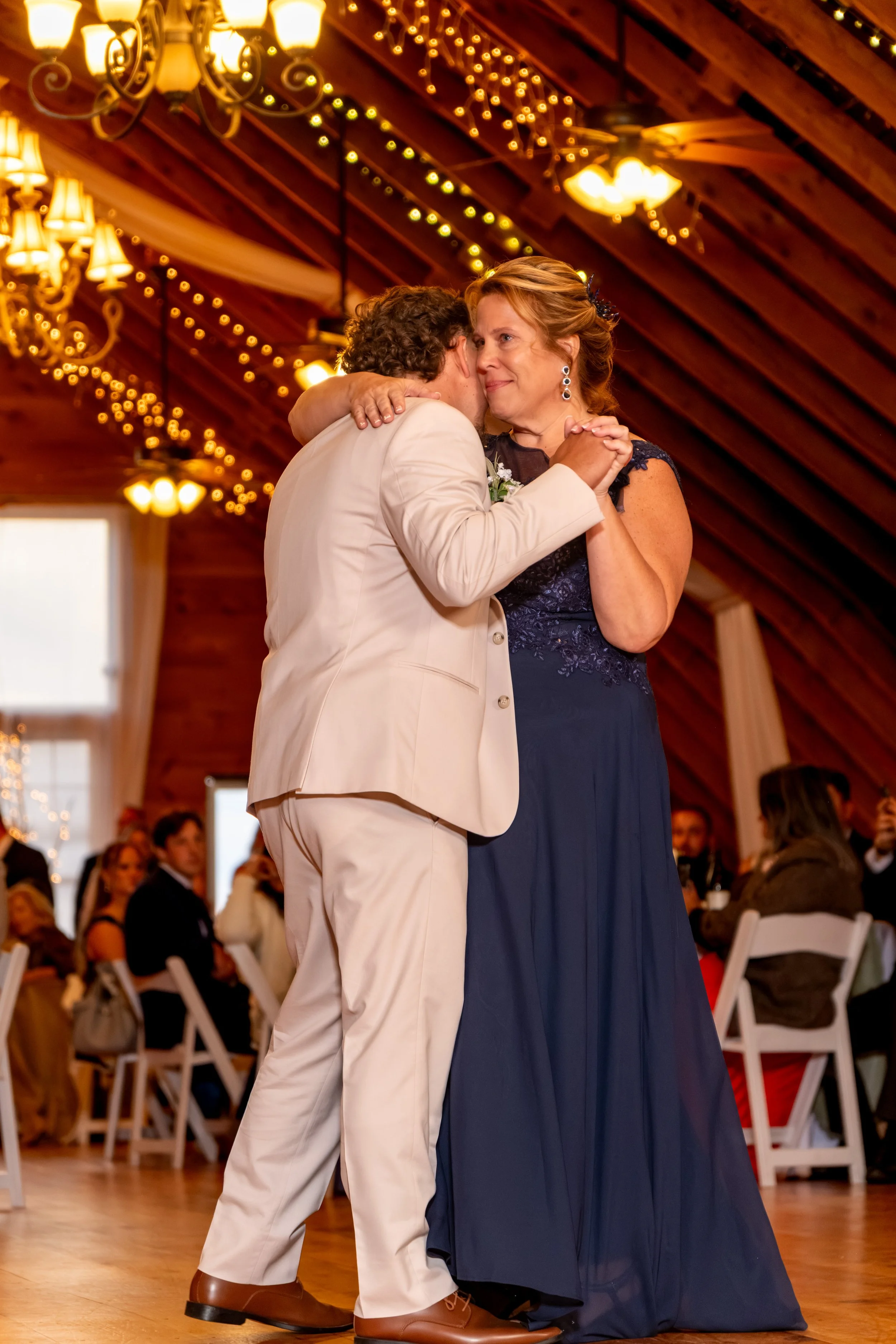 Andrew dancing with his mom in the barn as she rests her head on his shoulder at the Maine Wedding Barn and Event Center in Minot Maine fall wedding photography VMG Productions