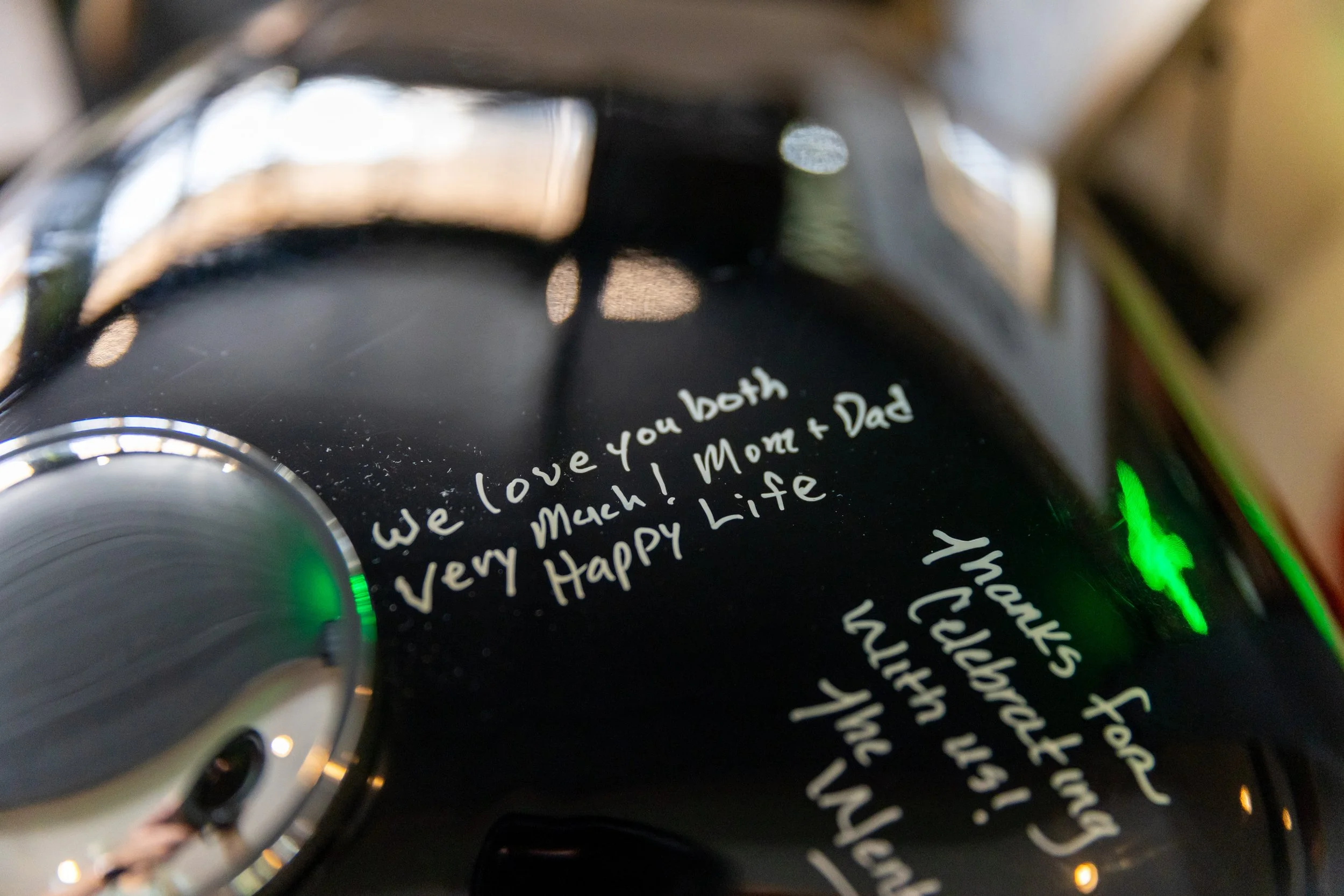 Close up of handwritten guest messages in white paint marker on black Harley Davidson motorcycle tank wedding guest book at Wentworth Inn Jackson New Hampshire wedding 2024
