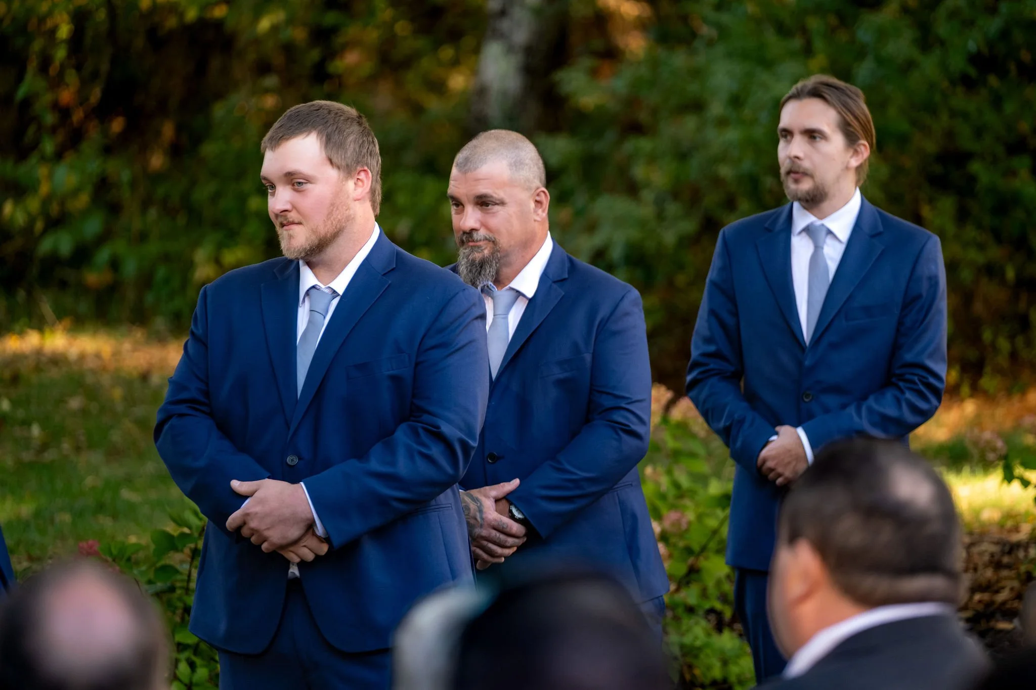 Sam's groomsmen in navy suits watching the ceremony with their hands clasped at Boothbay Playhouse in Boothbay Maine fall wedding photography VMG Productions