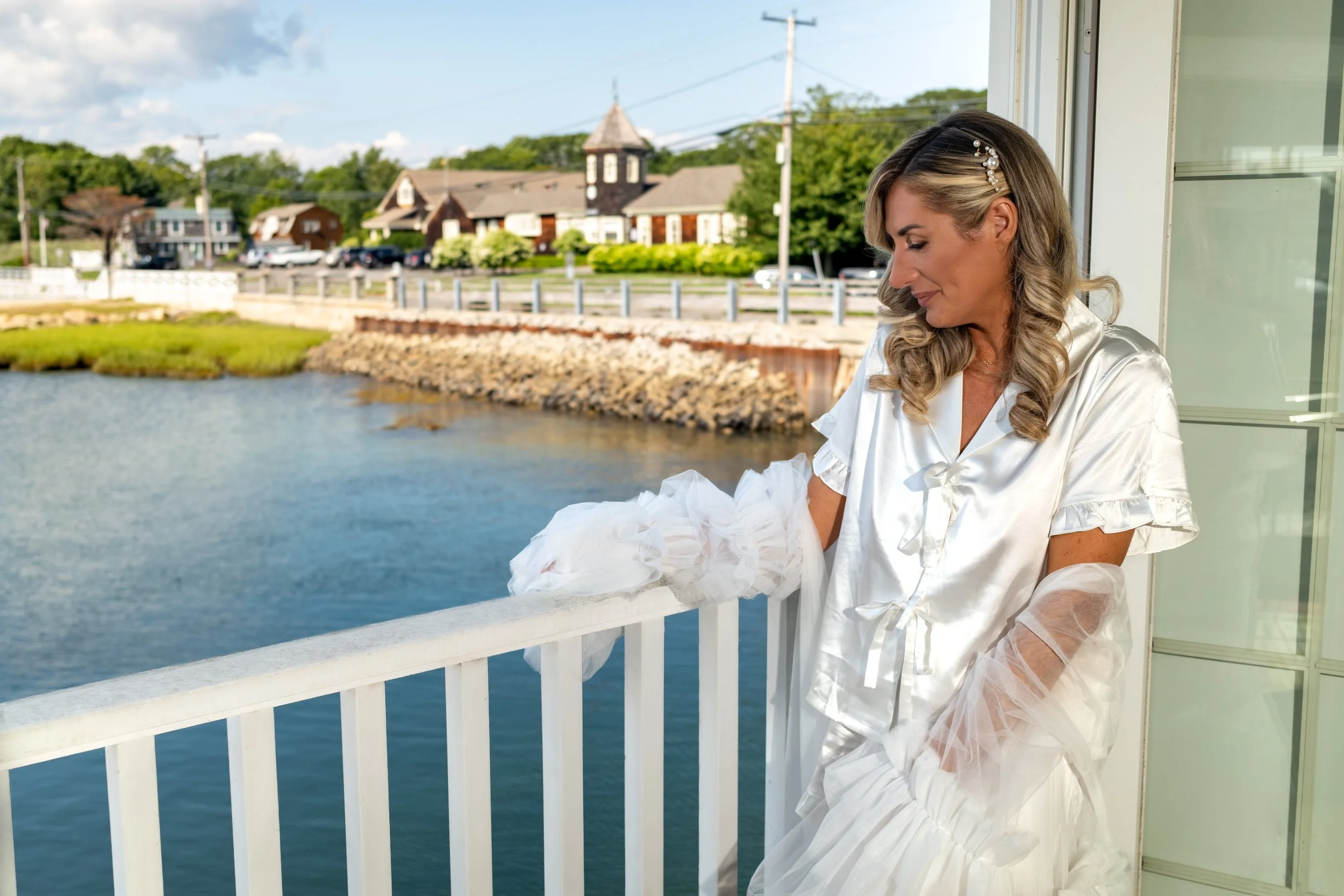 Ashley Draper on the balcony taking in the coastal breeze over the harbor while getting ready at The Breakwater Inn in Kennebunkport Maine summer wedding photography VMG Productions
