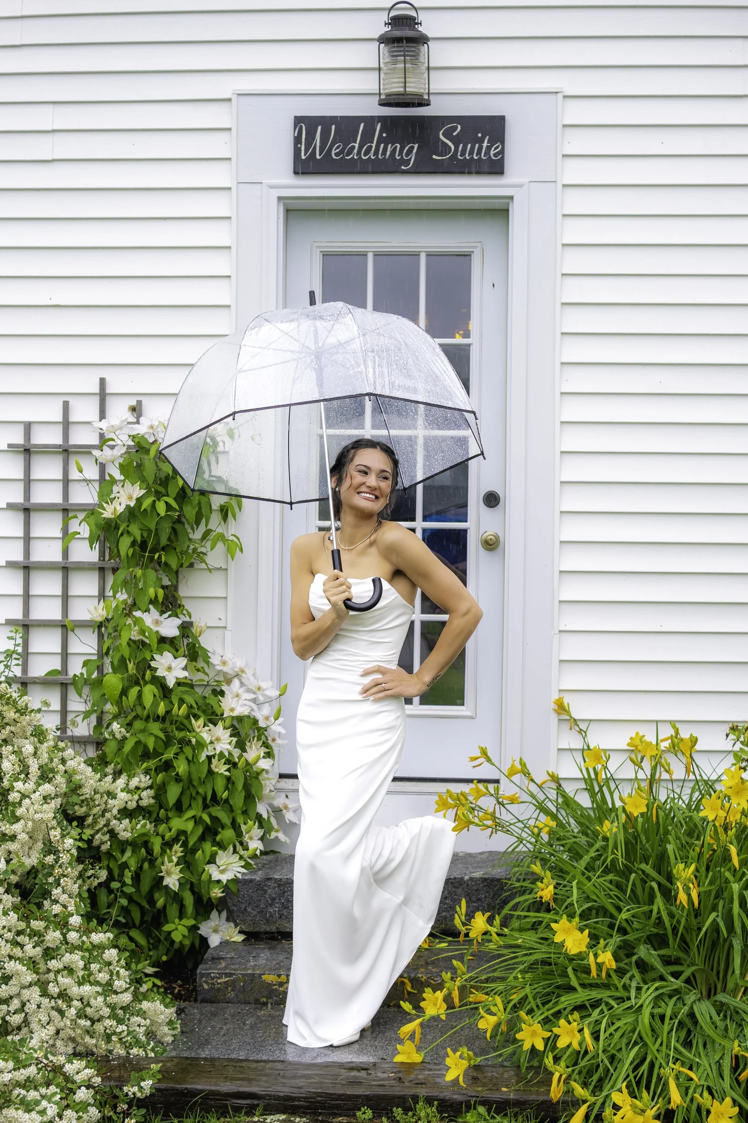 Bride smiling with clear umbrella outside Wedding Suite door during rainy wedding day at Harmony Hill Farm Warren Maine