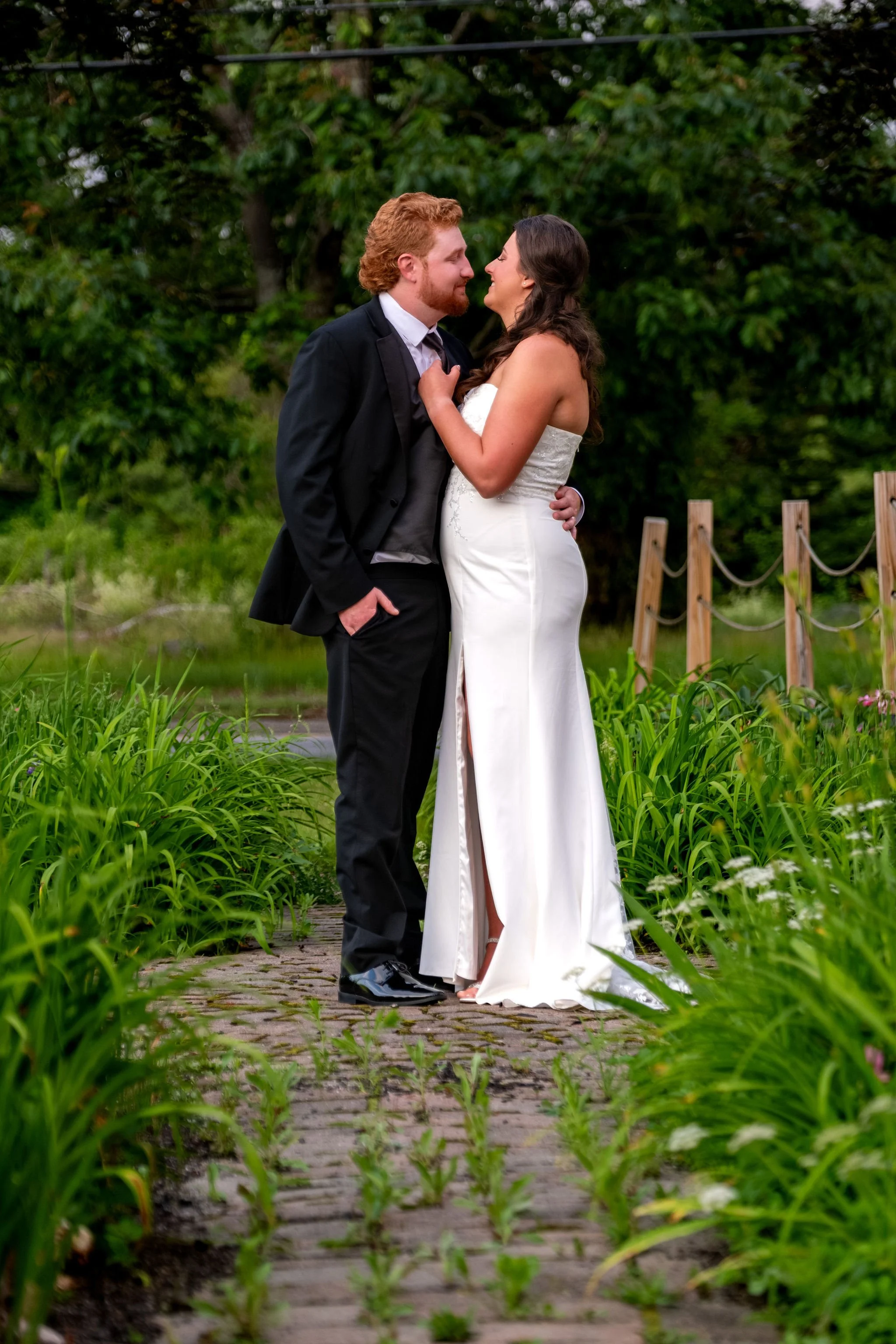 Alyssa and Colby nose to nose on the garden path at sunset at the 1888 Barn Bethel Maine summer wedding photography VMG Productions
