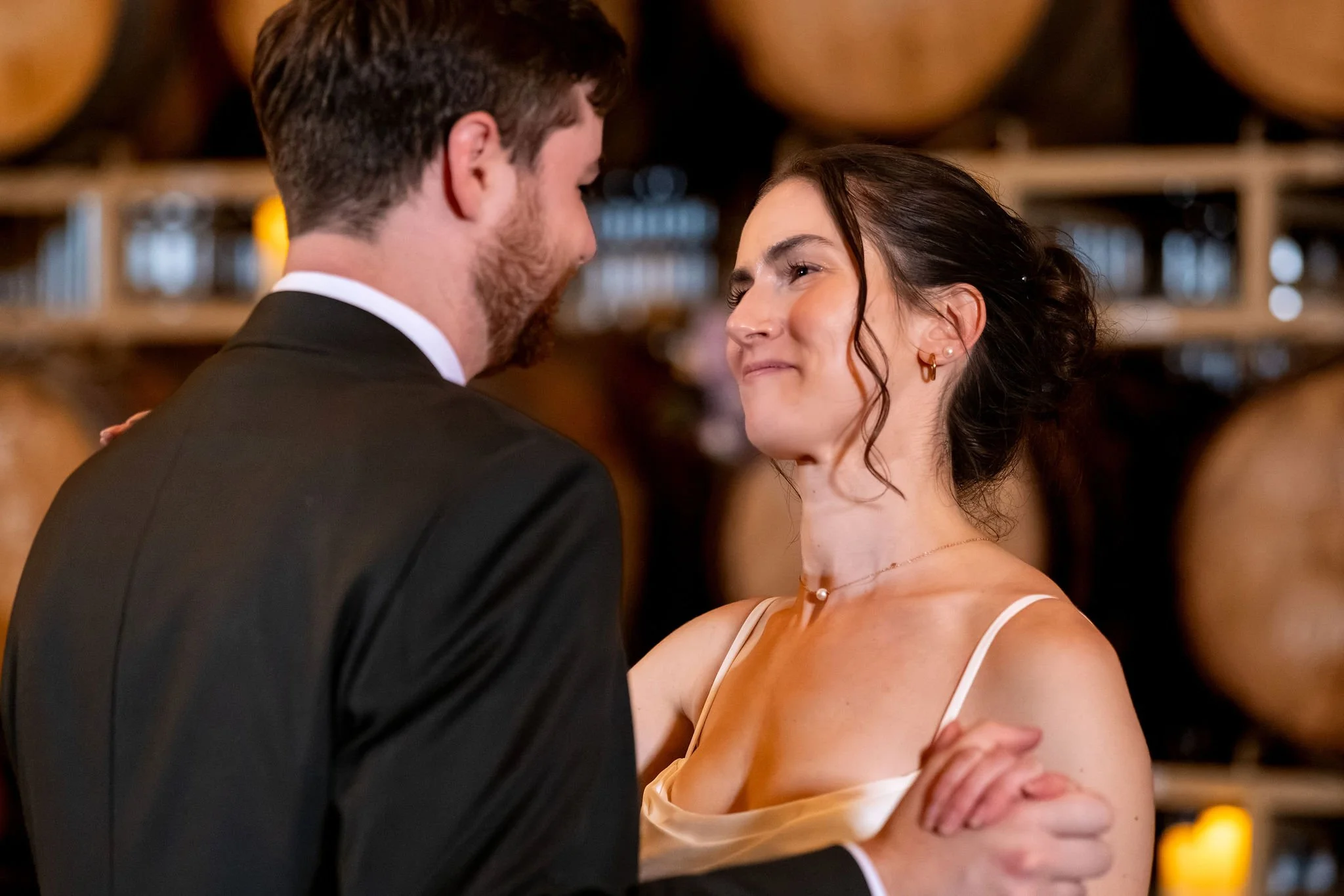 Victoria smiling up at Jack during their first dance at The Cellars at Allagash Brewing Company in Portland Maine fall wedding photography VMG Productions