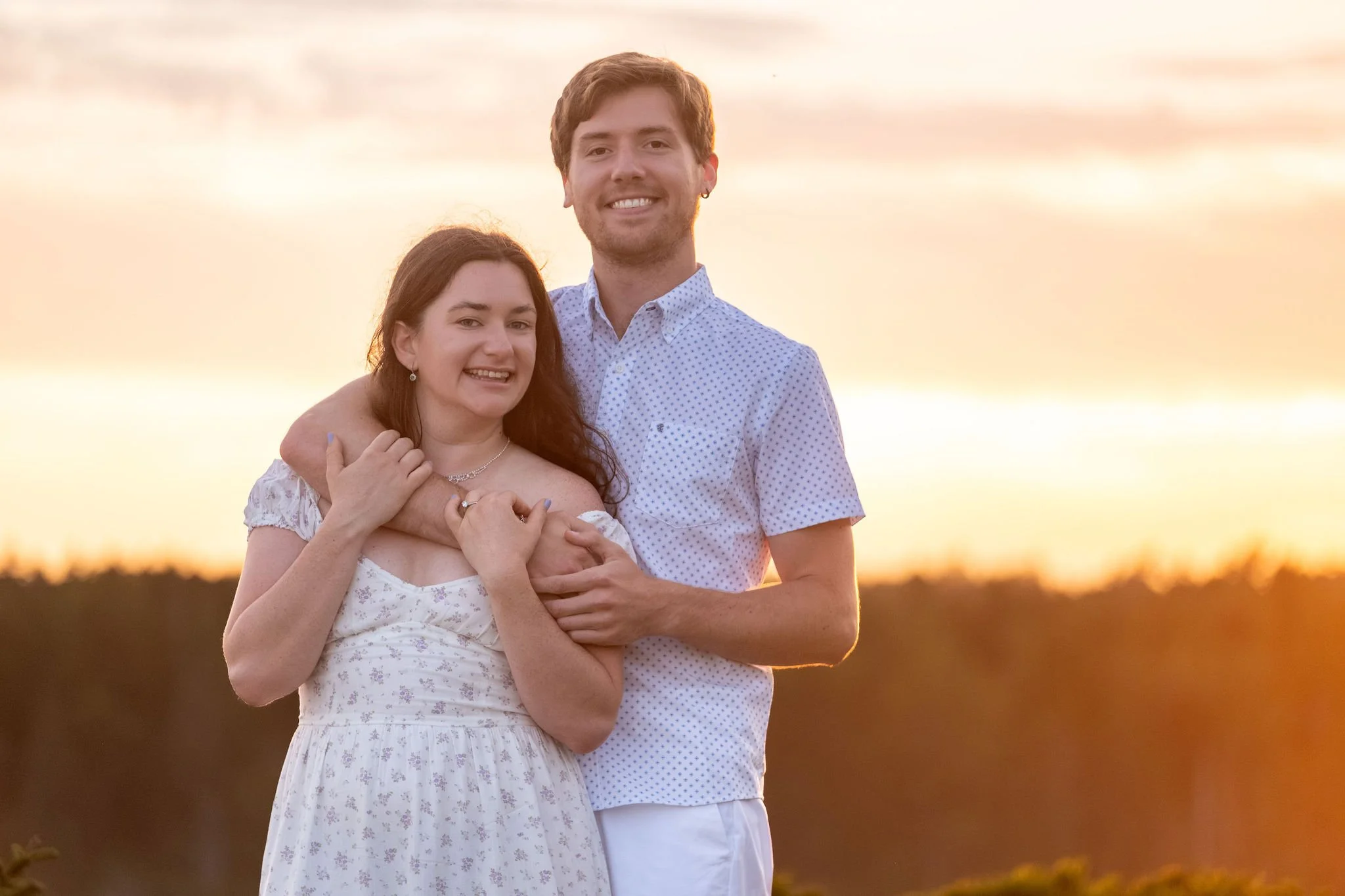 Kirstie and Lucas smiling together in the last of the golden light at Reid State Park in Georgetown Maine engagement photography VMG Productions