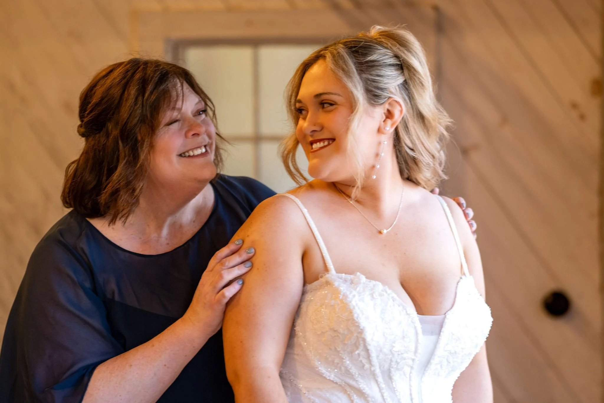 Ellie and her mom laughing together with her mom's hands on her shoulders at Boothbay Playhouse in Boothbay Maine fall wedding photography VMG Productions
