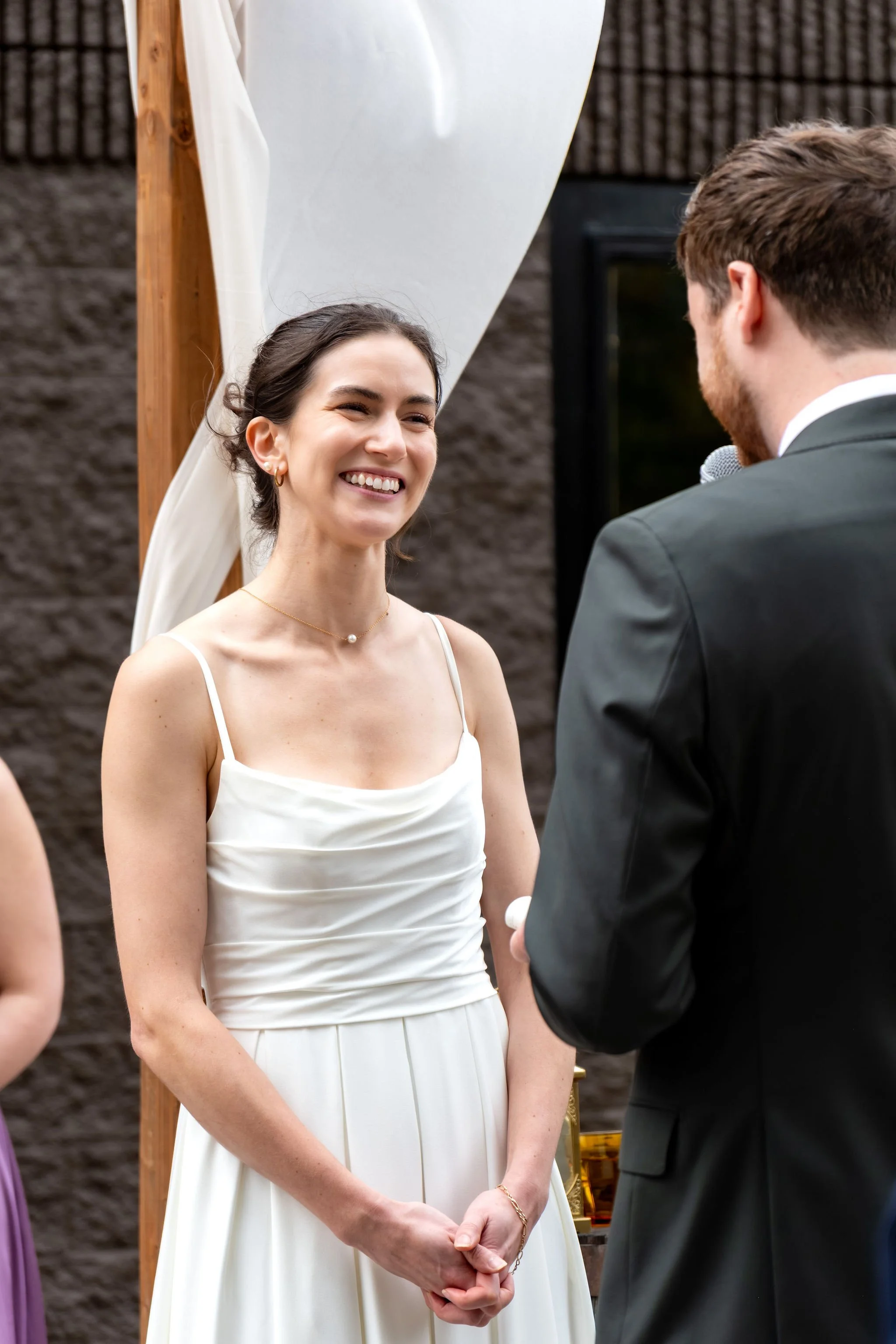 Victoria beaming as she listens to Jack's vows at The Cellars at Allagash Brewing Company in Portland Maine fall wedding photography VMG Productions