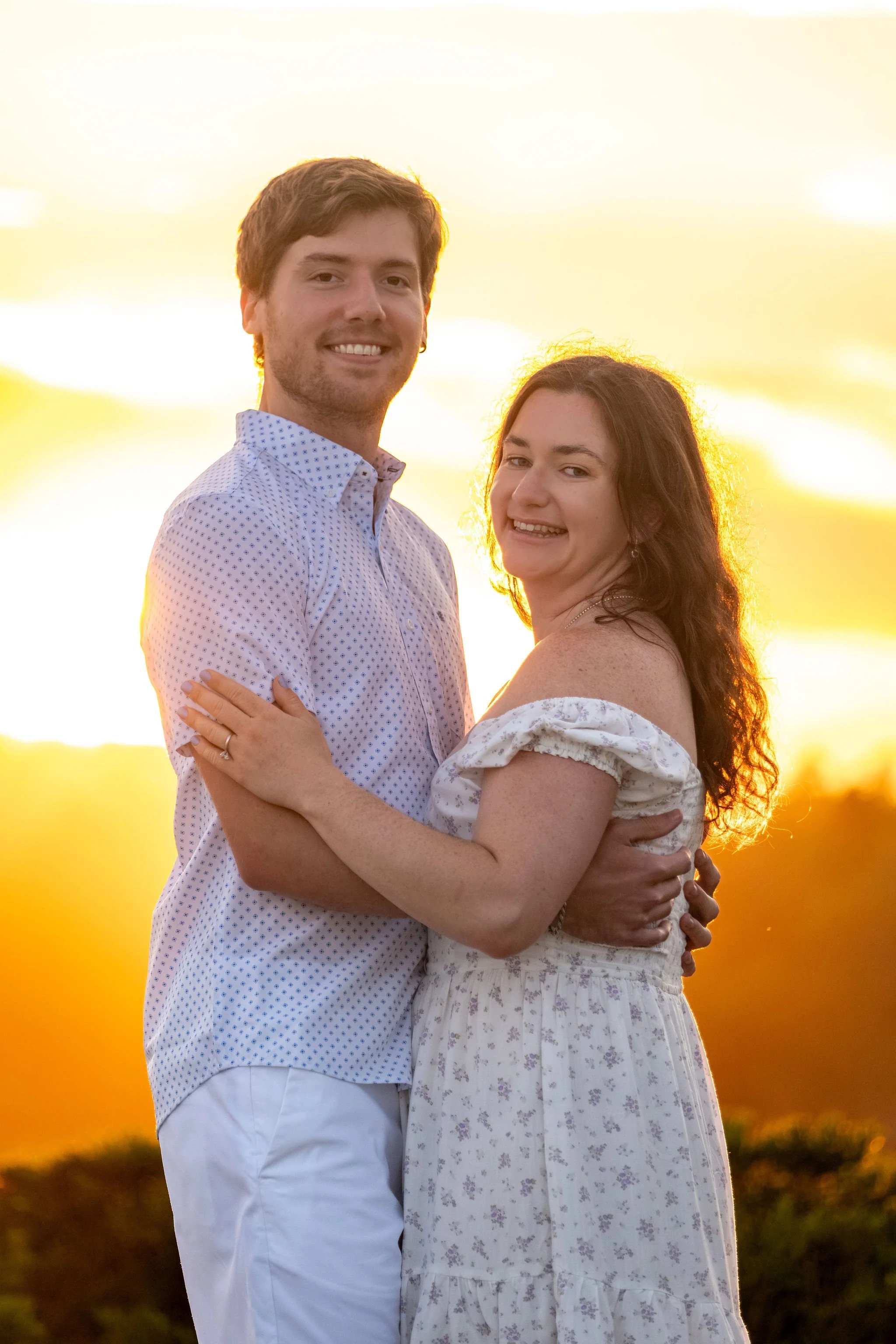 Kirstie and Lucas smiling at each other in golden backlight at sunset at Reid State Park in Georgetown Maine engagement photography VMG Productions