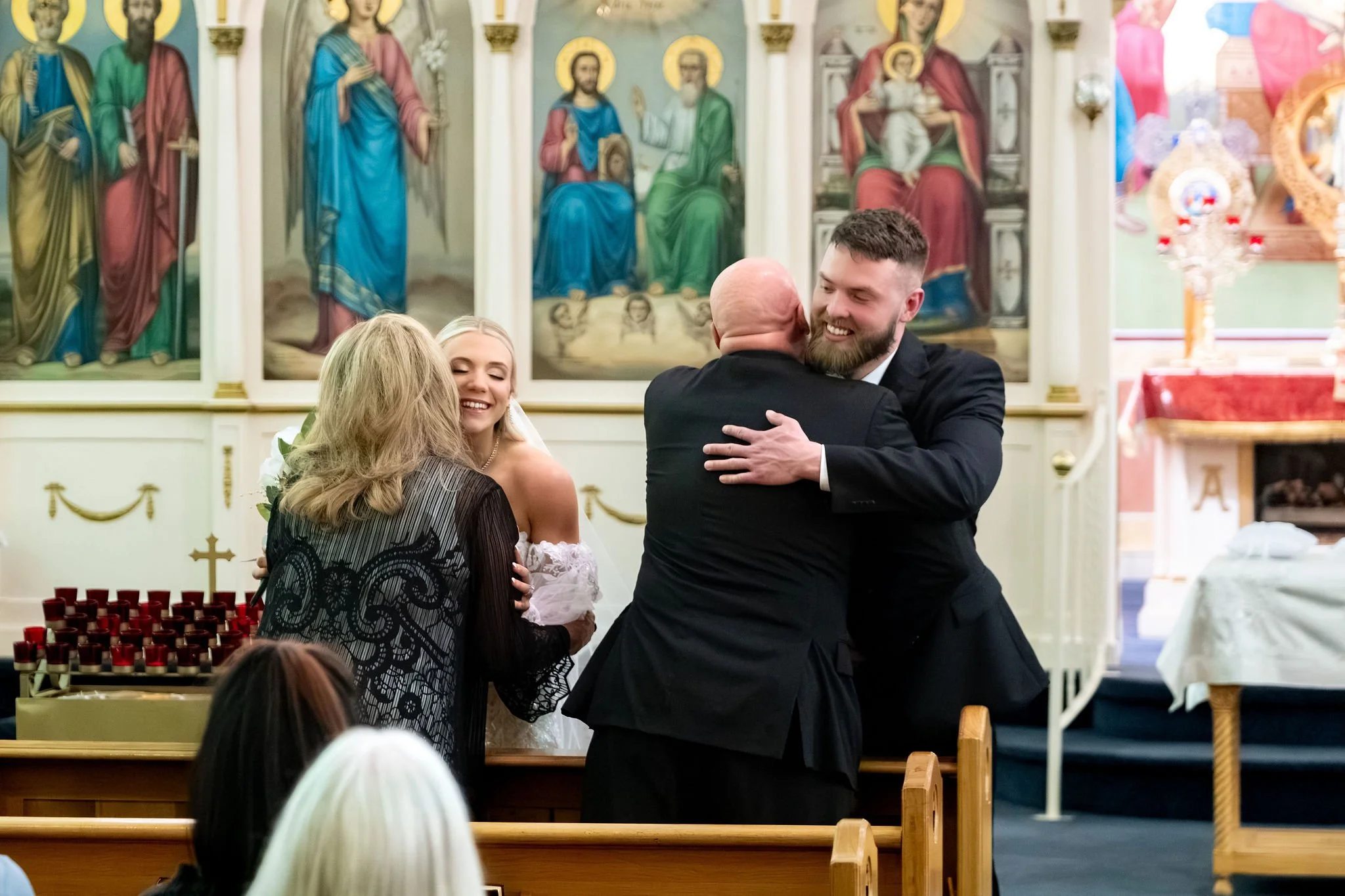 Jeremiah and Vienna family members embrace the newly married couple following the ceremony at Holy Trinity Greek Orthodox Church Portland Maine spring wedding photography VMG Productions