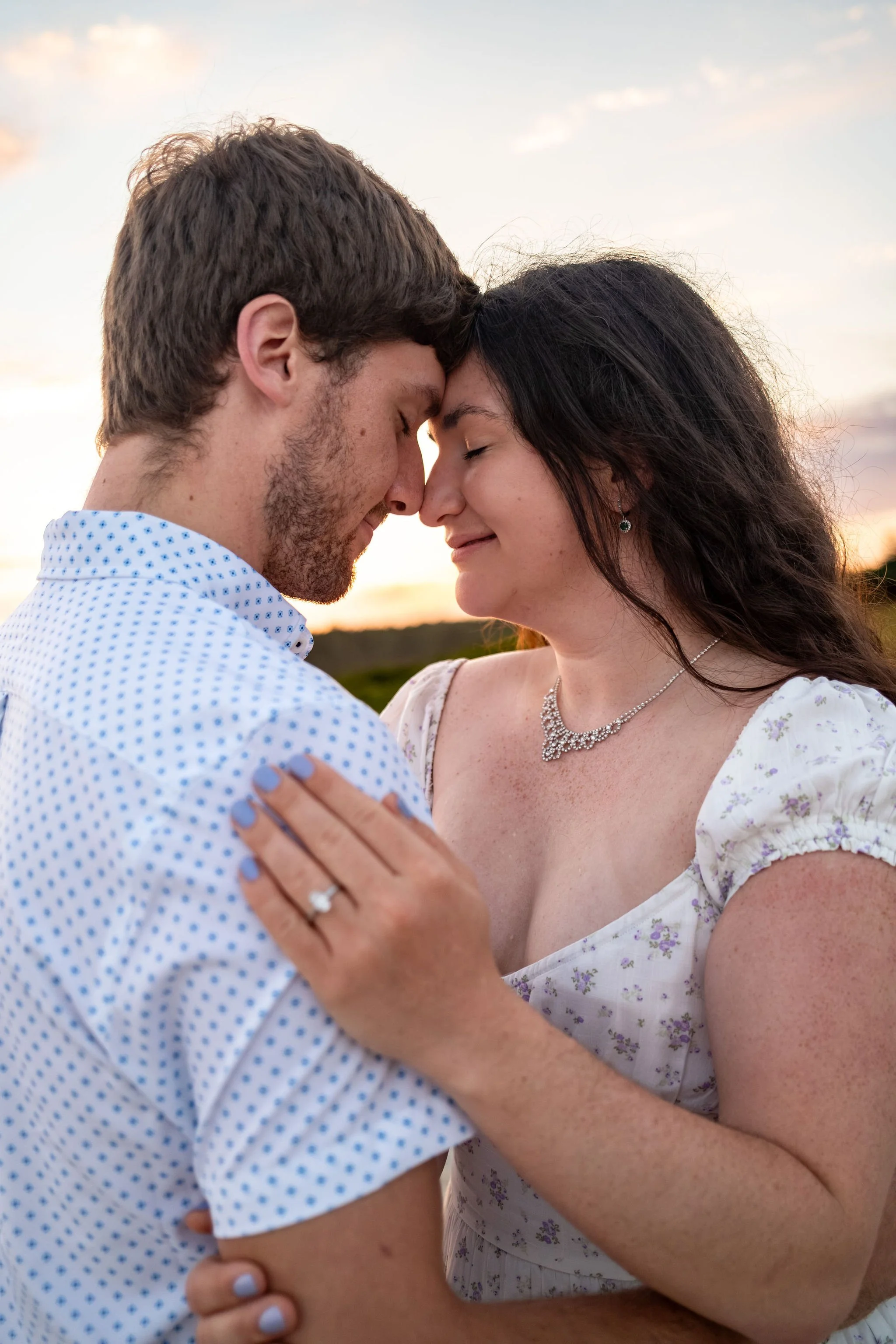 Kirstie's engagement ring on her hand against Lucas's chest with their foreheads together at Reid State Park in Georgetown Maine engagement photography VMG Productions