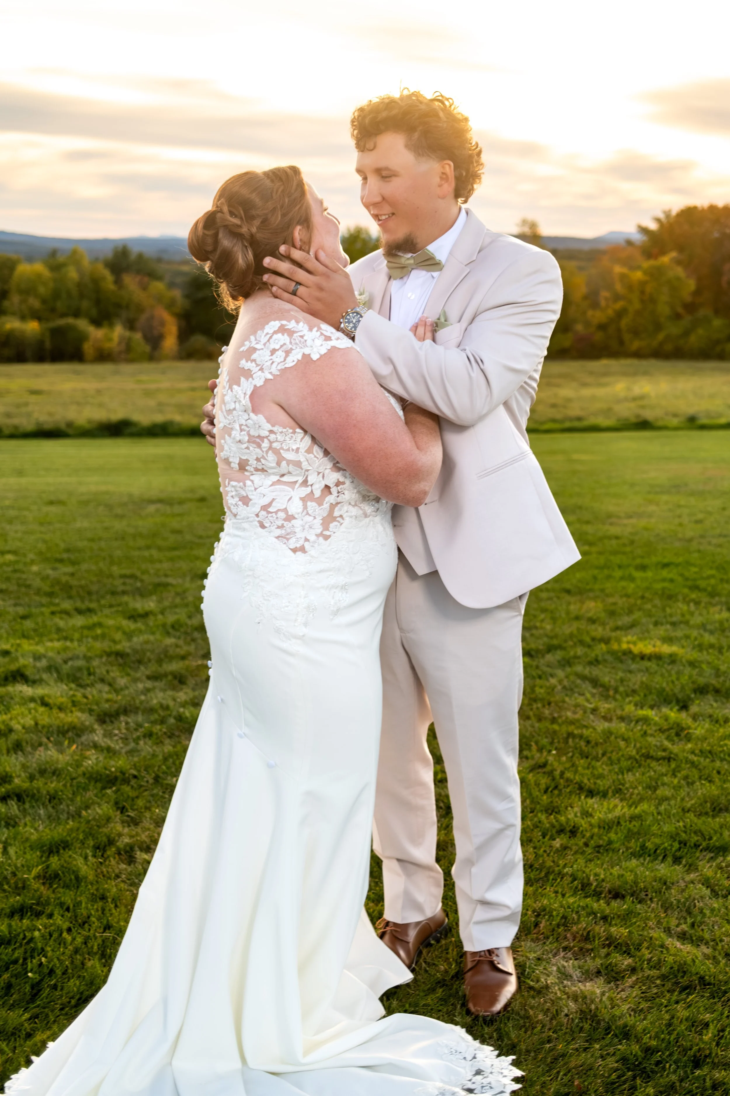 Erika touching Andrew's cheek as he kisses her in the sunset light at the Maine Wedding Barn and Event Center in Minot Maine fall wedding photography VMG Productions