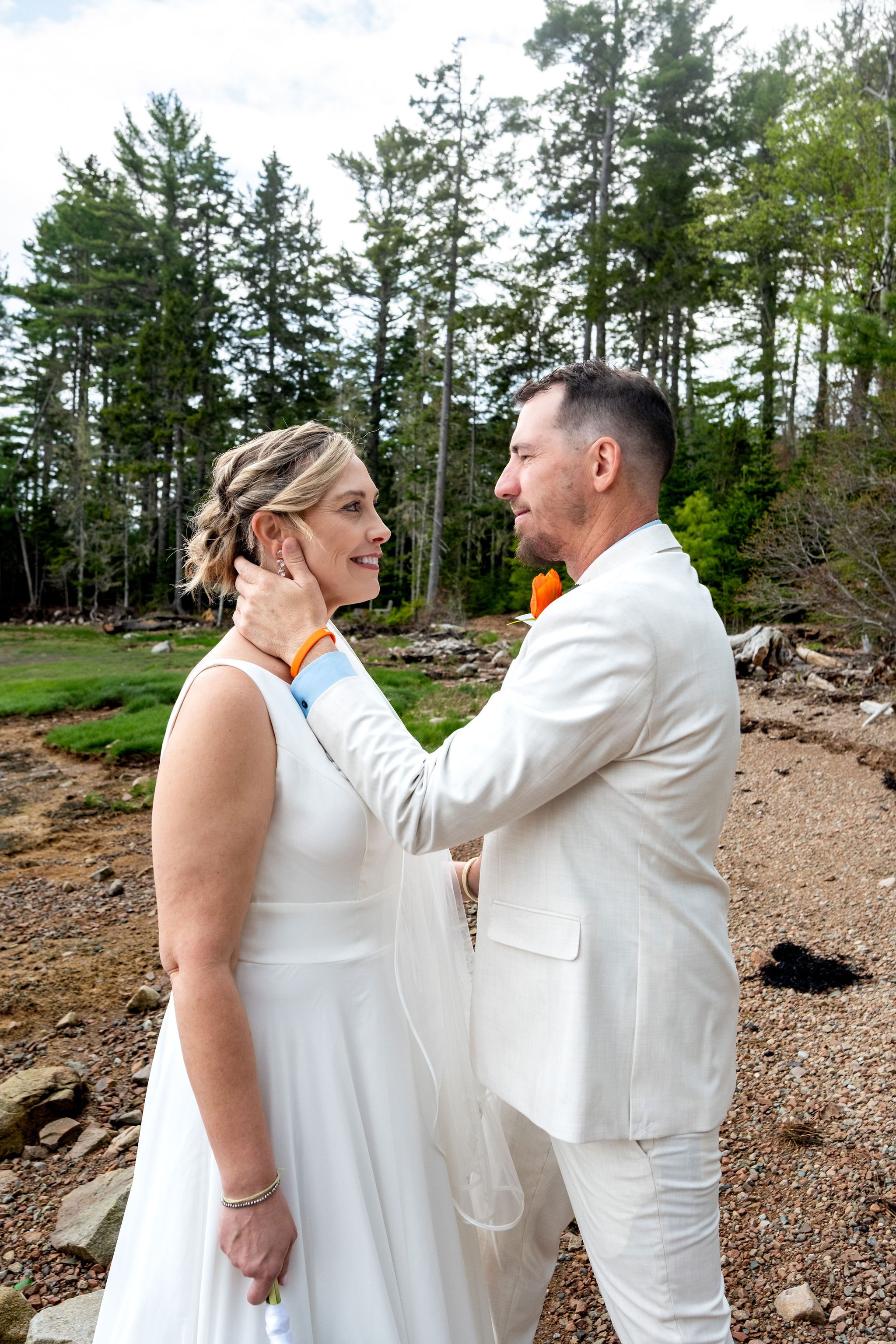 Alli and Adam Baudoin sharing their first look on the rocky shoreline of Somes Sound at their private residence spring wedding in Mount Desert Maine wedding photography VMG Productions