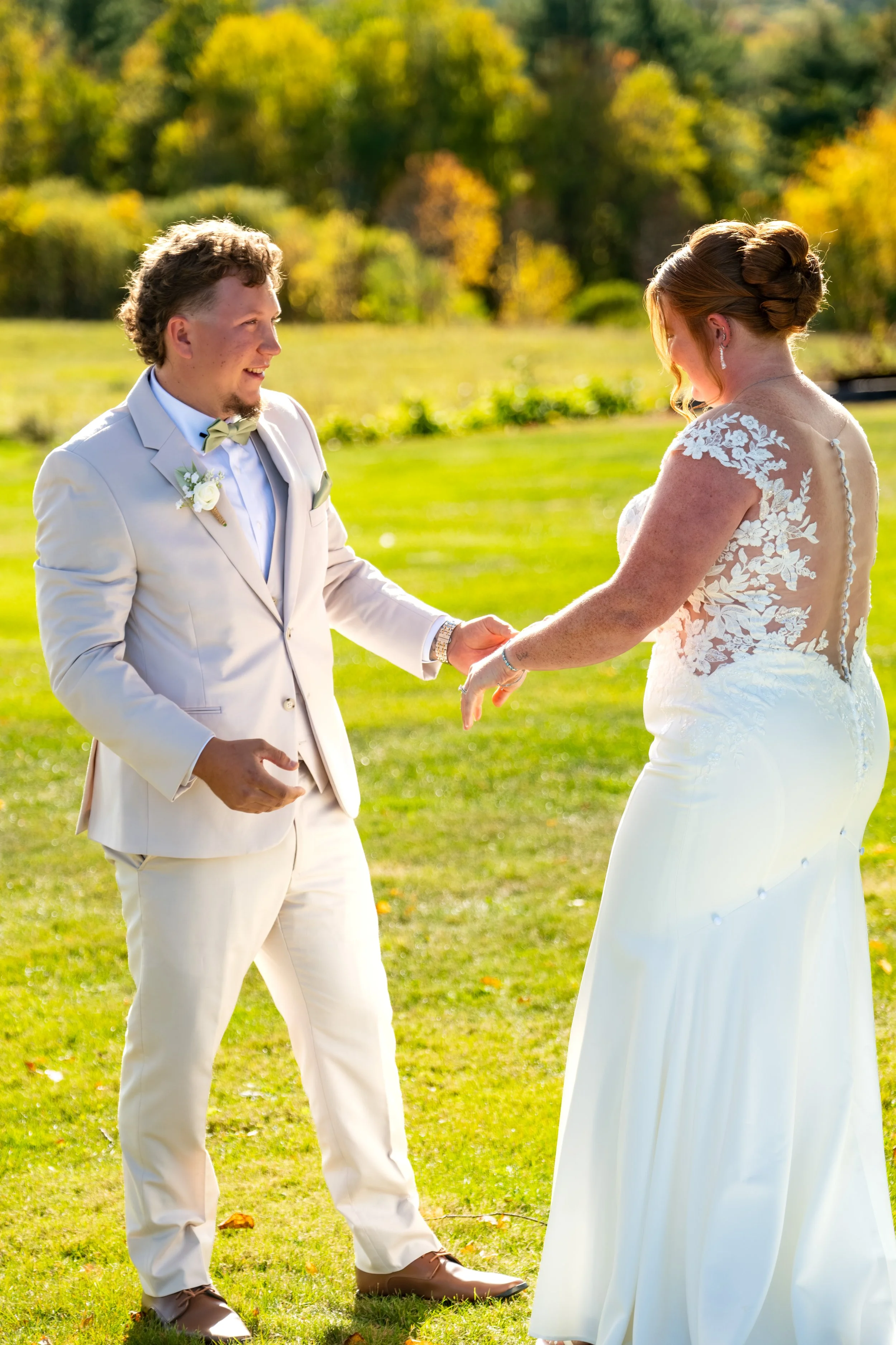 Andrew smiling as he takes Erika's hand on the lawn at the Maine Wedding Barn and Event Center in Minot Maine fall wedding photography VMG Productions