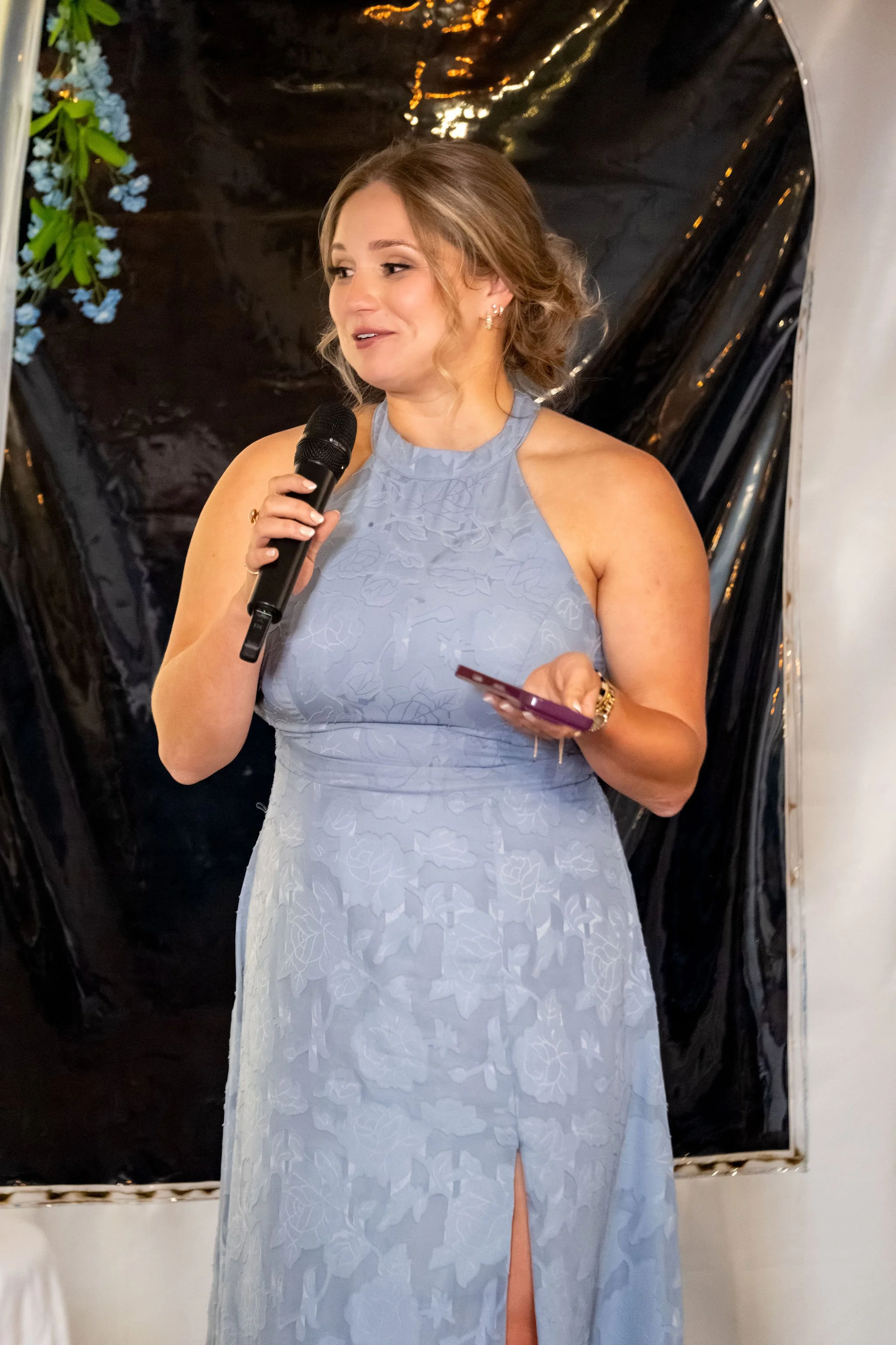 The maid of honor in dusty blue giving her speech into a microphone at The Lucerne Inn in Dedham Maine summer wedding photography VMG Productions