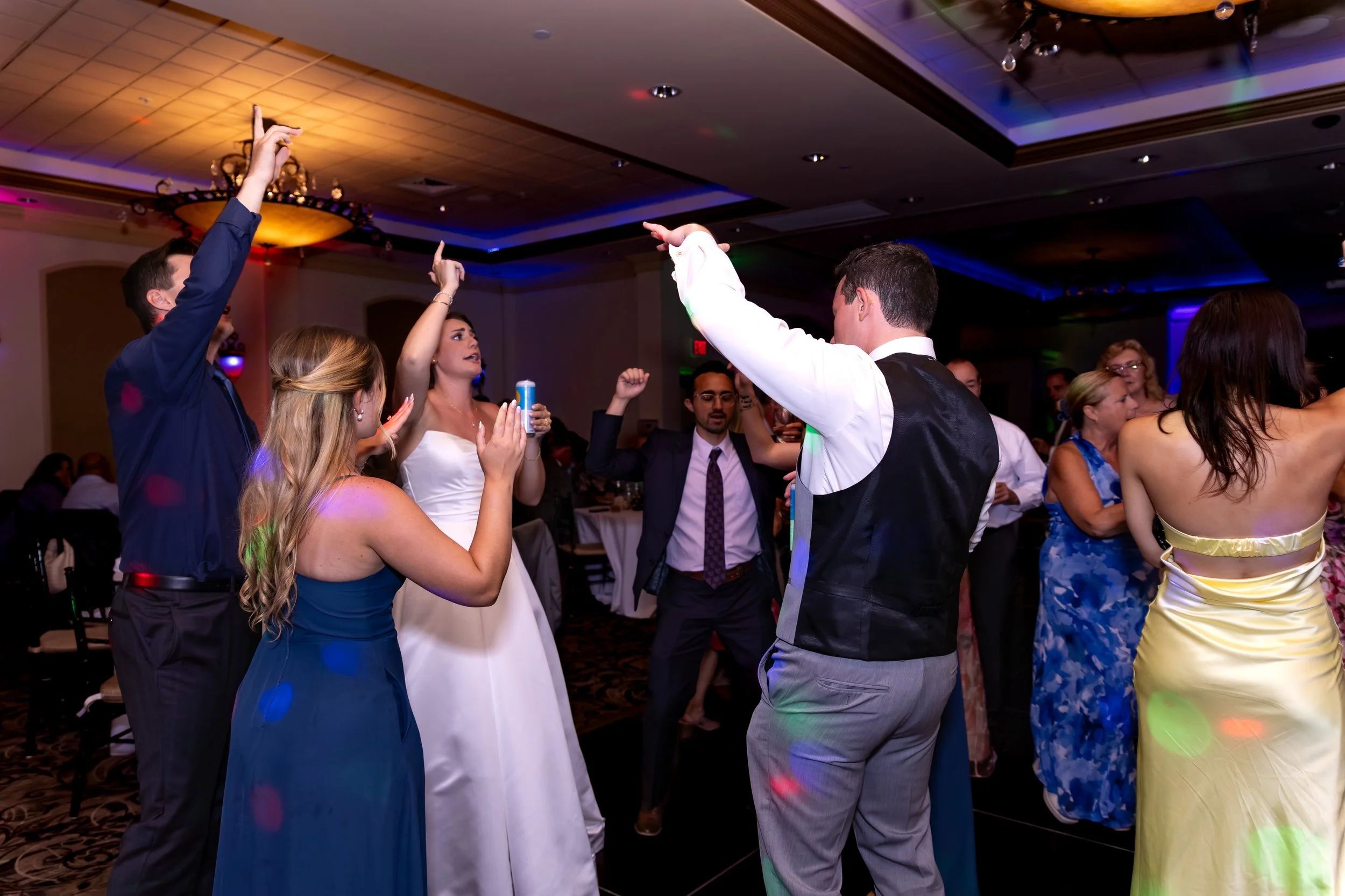 Caroline Pirolli dancing on the packed floor surrounded by guests under the colored lights at Union Bluff Hotel in York Maine wedding photography VMG Productions