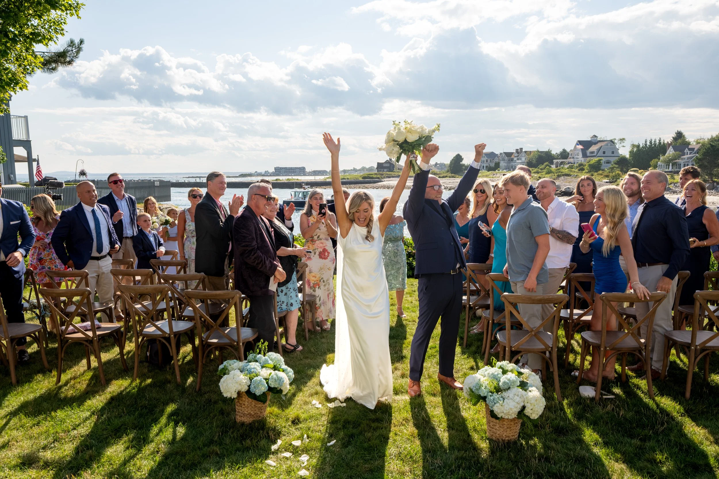 Ashley and Marc Draper celebrating with arms raised as they walk back up the aisle married at The Breakwater Inn in Kennebunkport Maine summer wedding photography VMG Productions