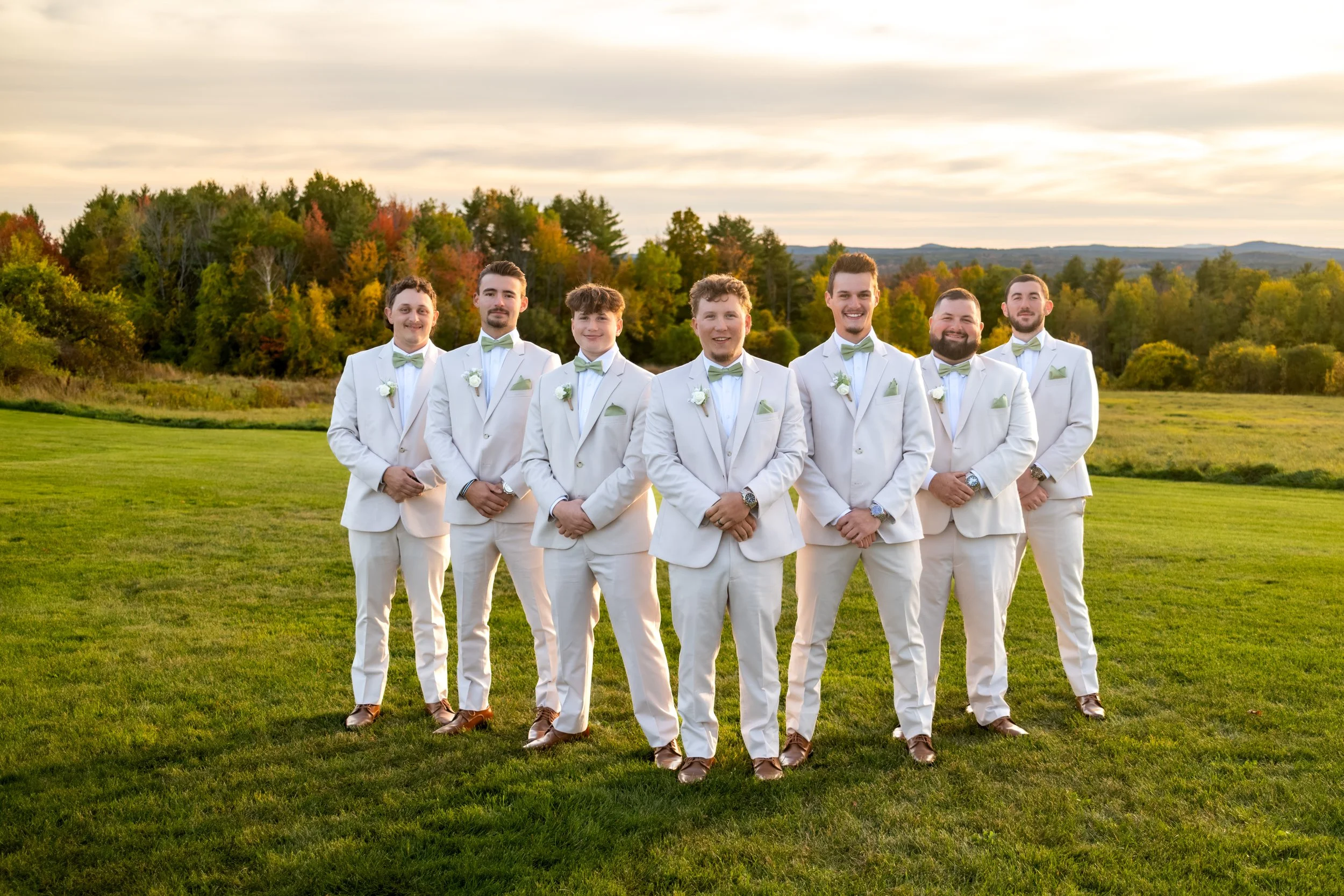 Andrew's groomsmen in tan suits standing in a line on the lawn at the Maine Wedding Barn and Event Center in Minot Maine fall wedding photography VMG Productions