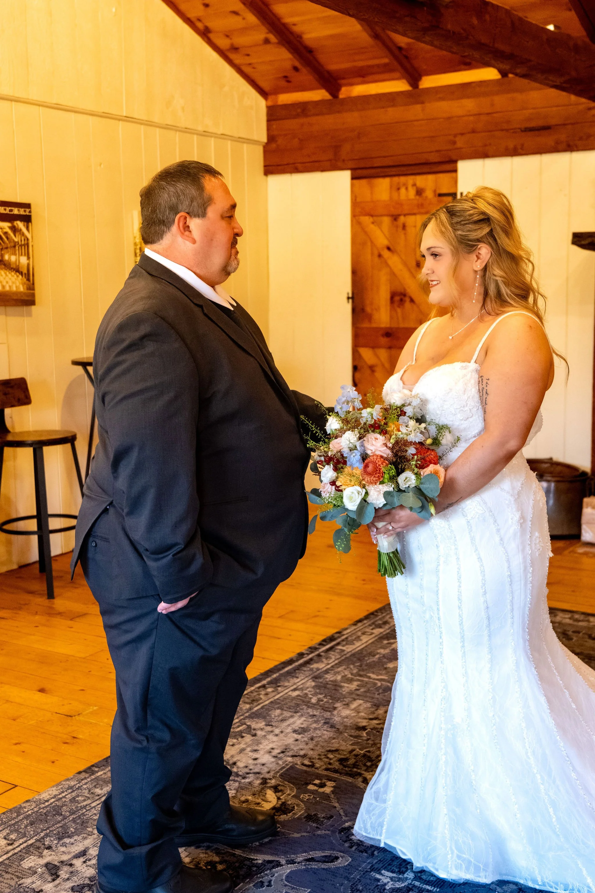 Ellie's dad looking at her with his hand in his pocket as she holds her bouquet at Boothbay Playhouse in Boothbay Maine fall wedding photography VMG Productions