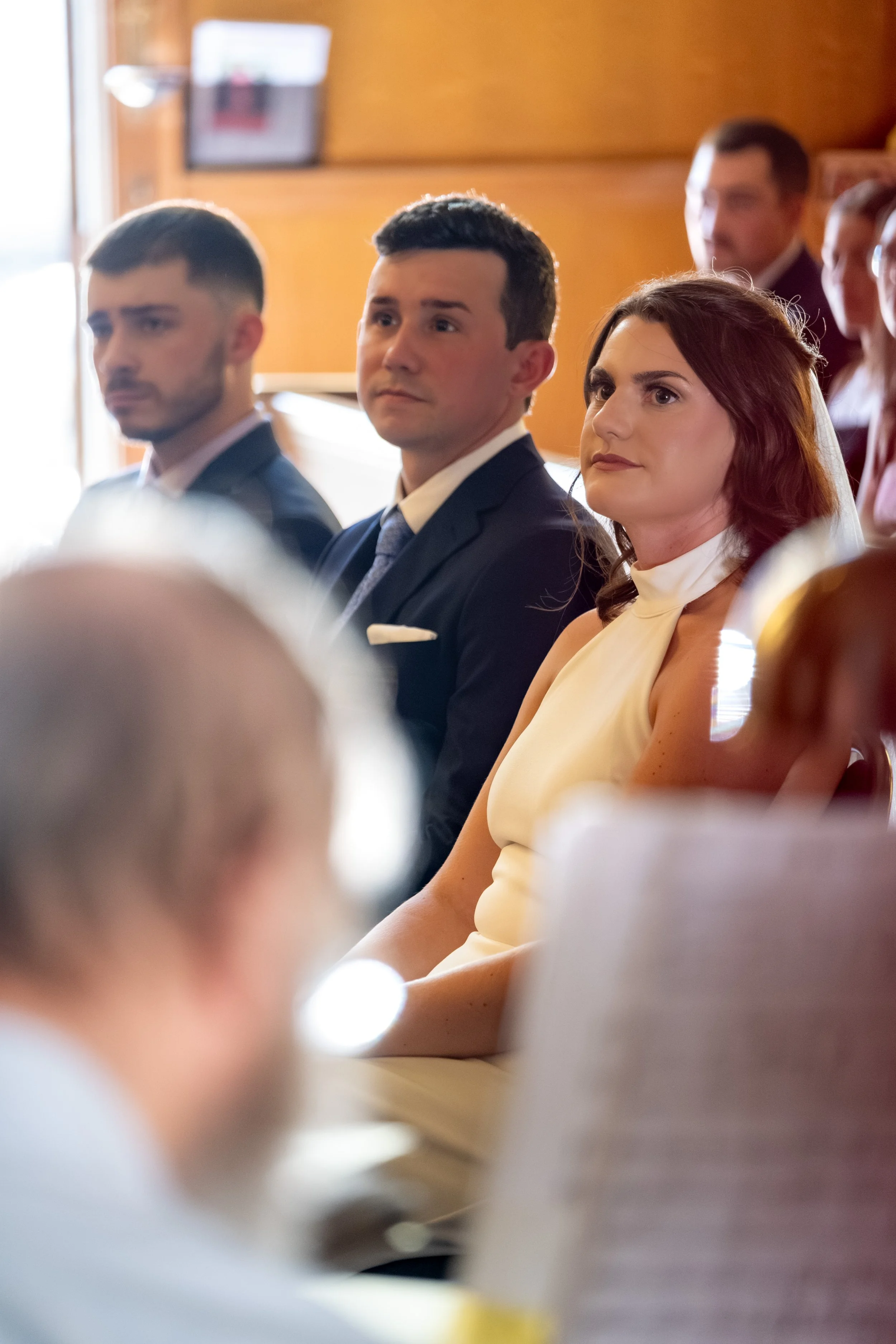 Caroline and Anthony Pirolli seated before the priest during the Catholic ceremony at Star of the Sea in York Maine wedding photography VMG Productions