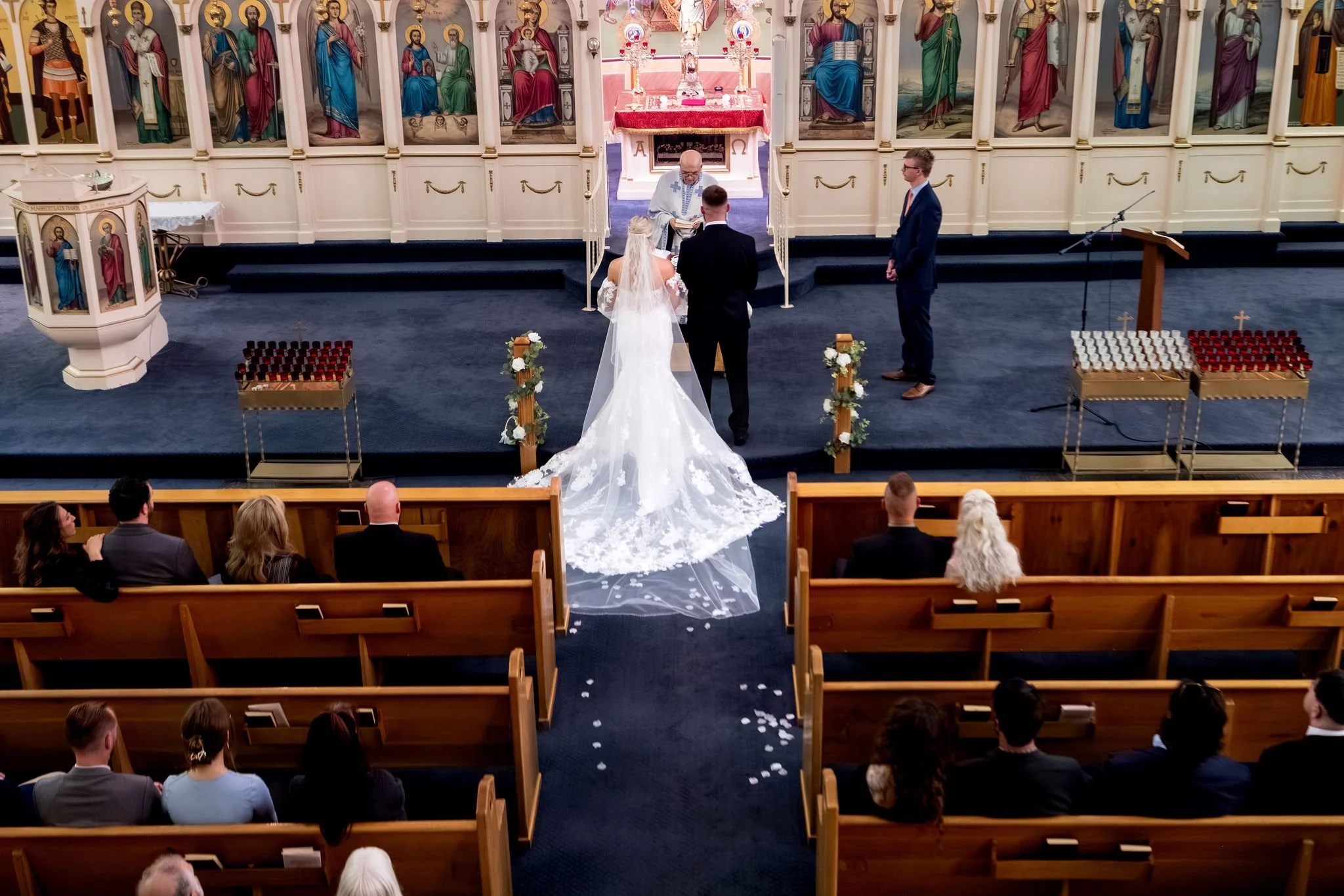 Jeremiah and Vienna elevated perspective showing the couple, officiant, and guests at Holy Trinity Greek Orthodox Church Portland Maine spring wedding photography VMG Productions