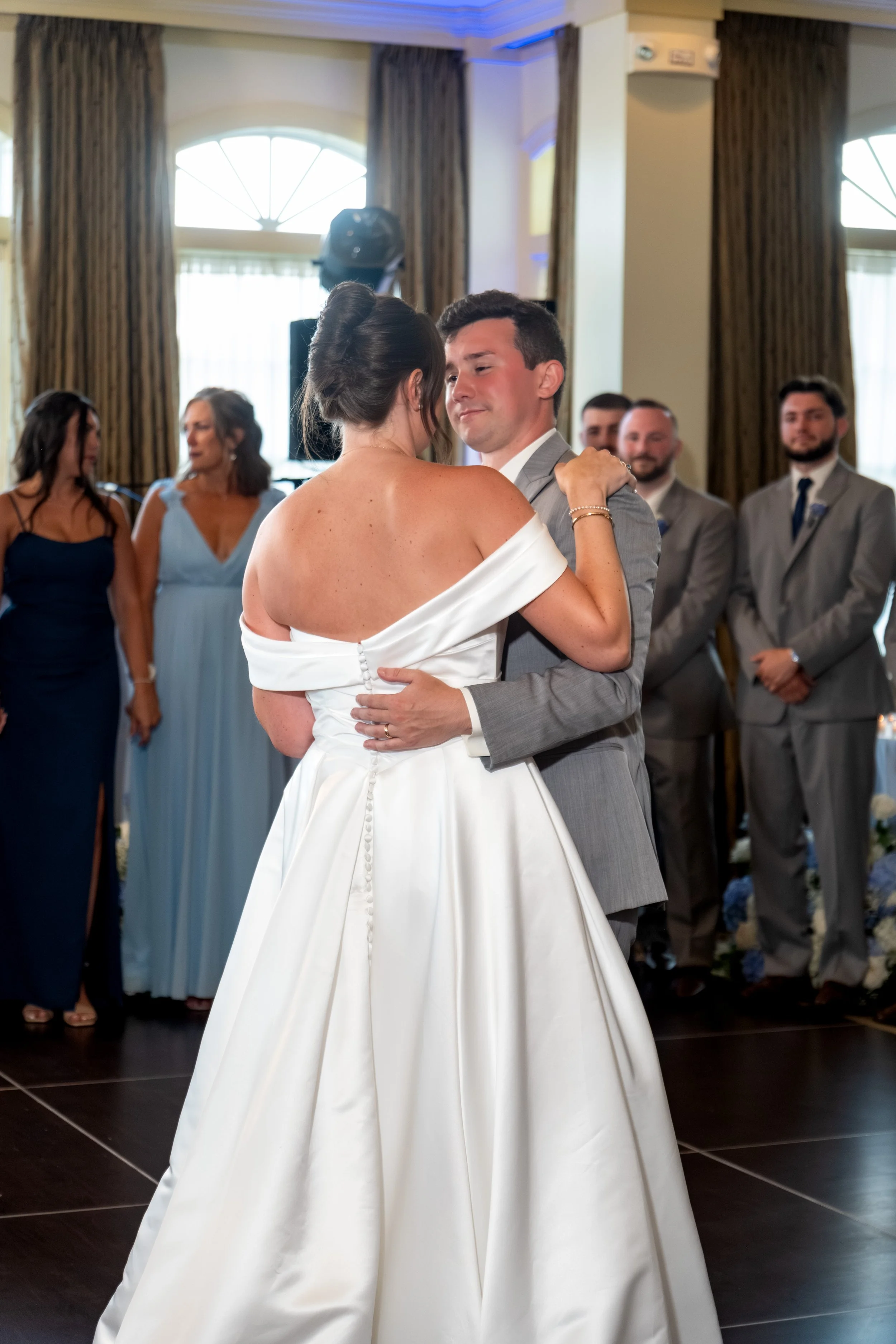 Anthony Pirolli holding Caroline close during their first dance with the buttons of her gown running down her back and his teary face over her shoulder at Union Bluff Hotel in York Maine wedding photography VMG Productions