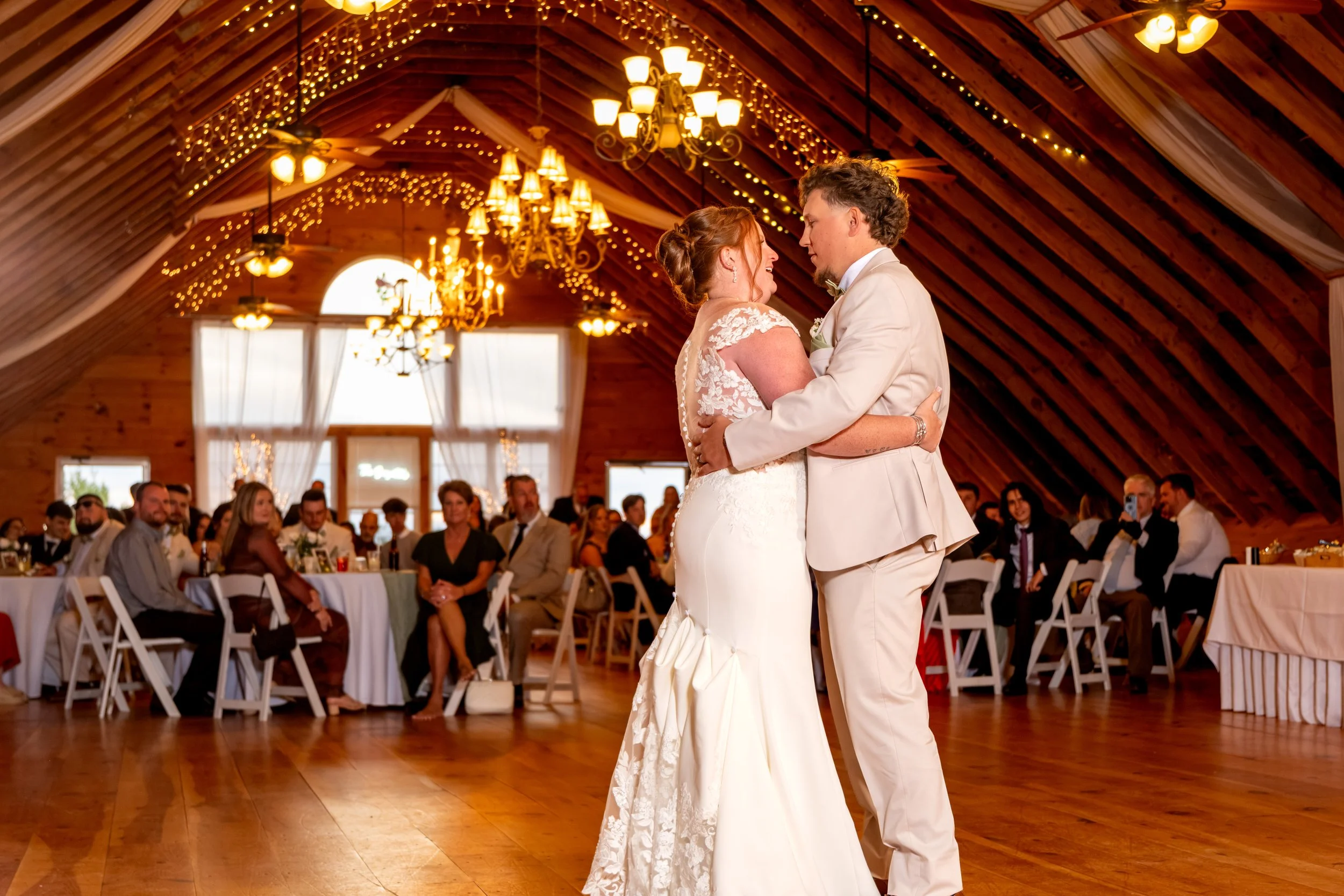 Erika and Andrew's first dance in the barn under the chandeliers and string lights at the Maine Wedding Barn and Event Center in Minot Maine fall wedding photography VMG Productions