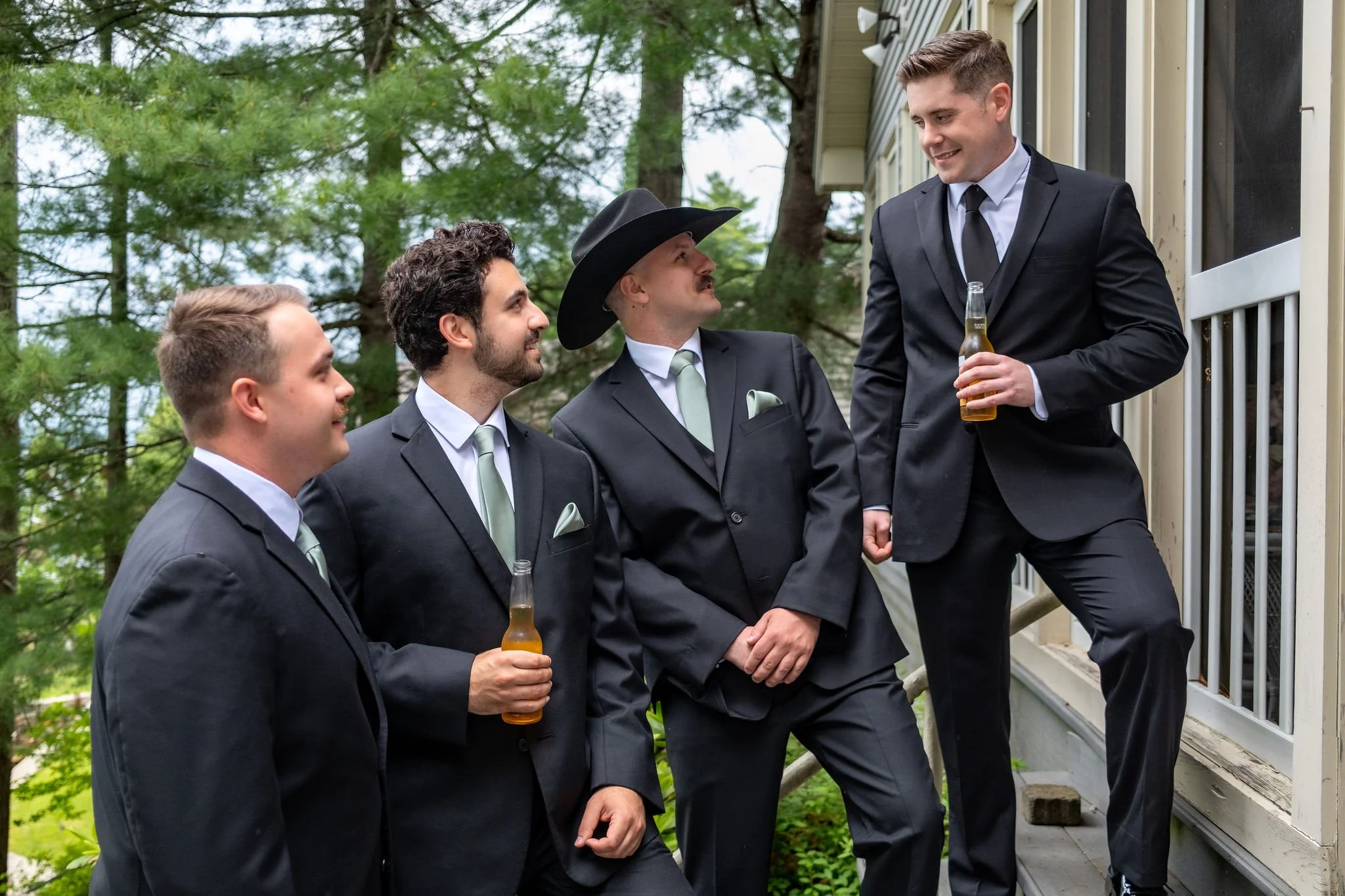 Ethan DeAngelis and his groomsmen with beers on the lake house porch steps in Belmont New Hampshire summer wedding photography VMG Productions