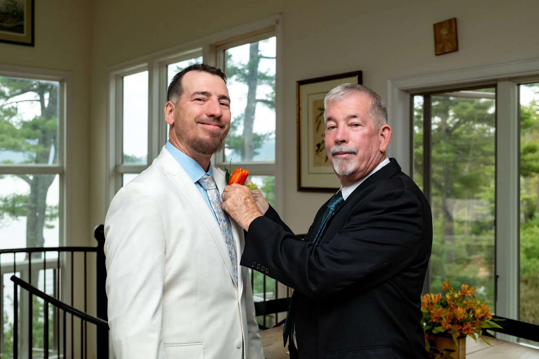 Father of the groom pinning the orange tulip boutonniere on Adam Baudoin at a private residence in Mount Desert Maine spring wedding photography VMG Productions