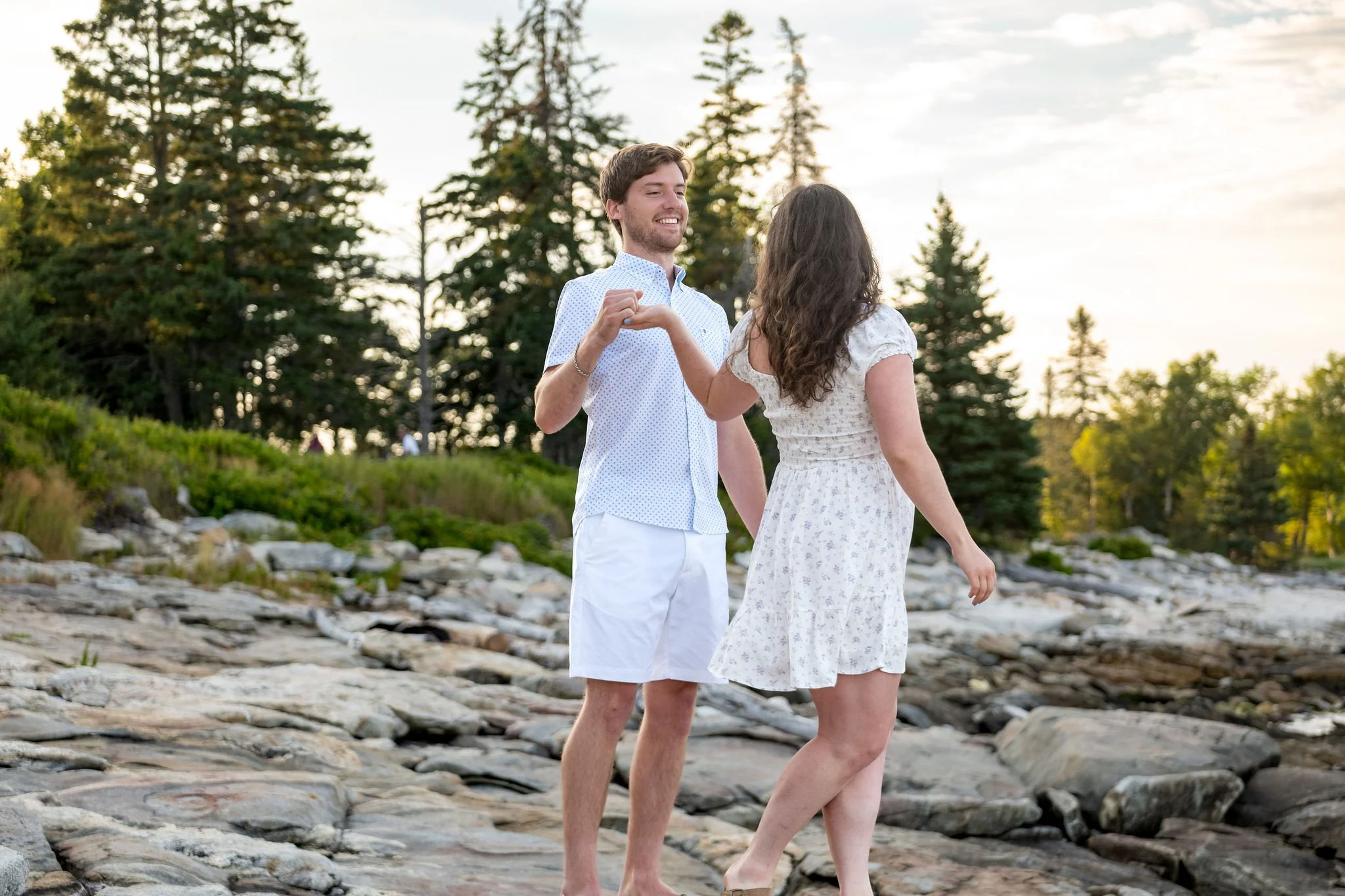 Kirstie and Lucas dancing and laughing on the granite ledges at Reid State Park in Georgetown Maine engagement photography VMG Productions