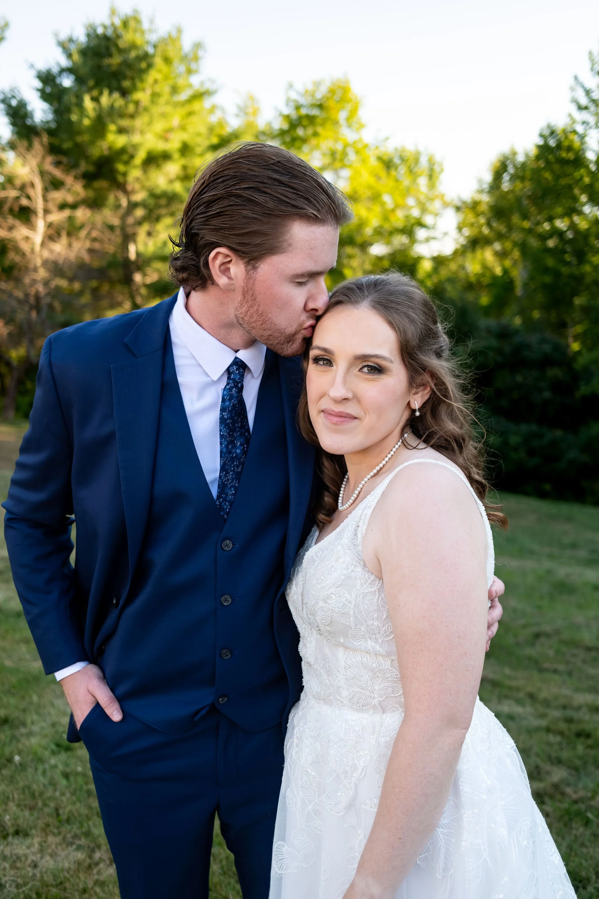 Zachary kissing Hollie on the temple in the golden evening light at The Lucerne Inn in Dedham Maine summer wedding photography VMG Productions