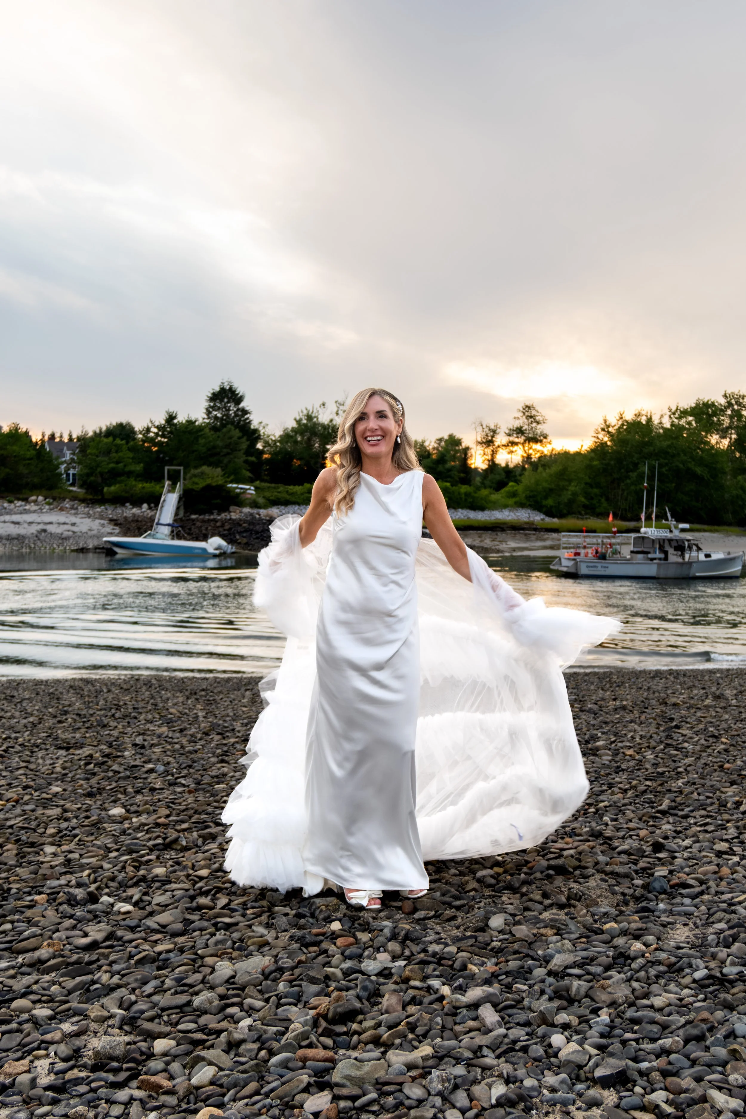 Ashley Draper with her tulle wrap in motion on the pebble beach at sunset at The Breakwater Inn in Kennebunkport Maine summer wedding photography VMG Productions