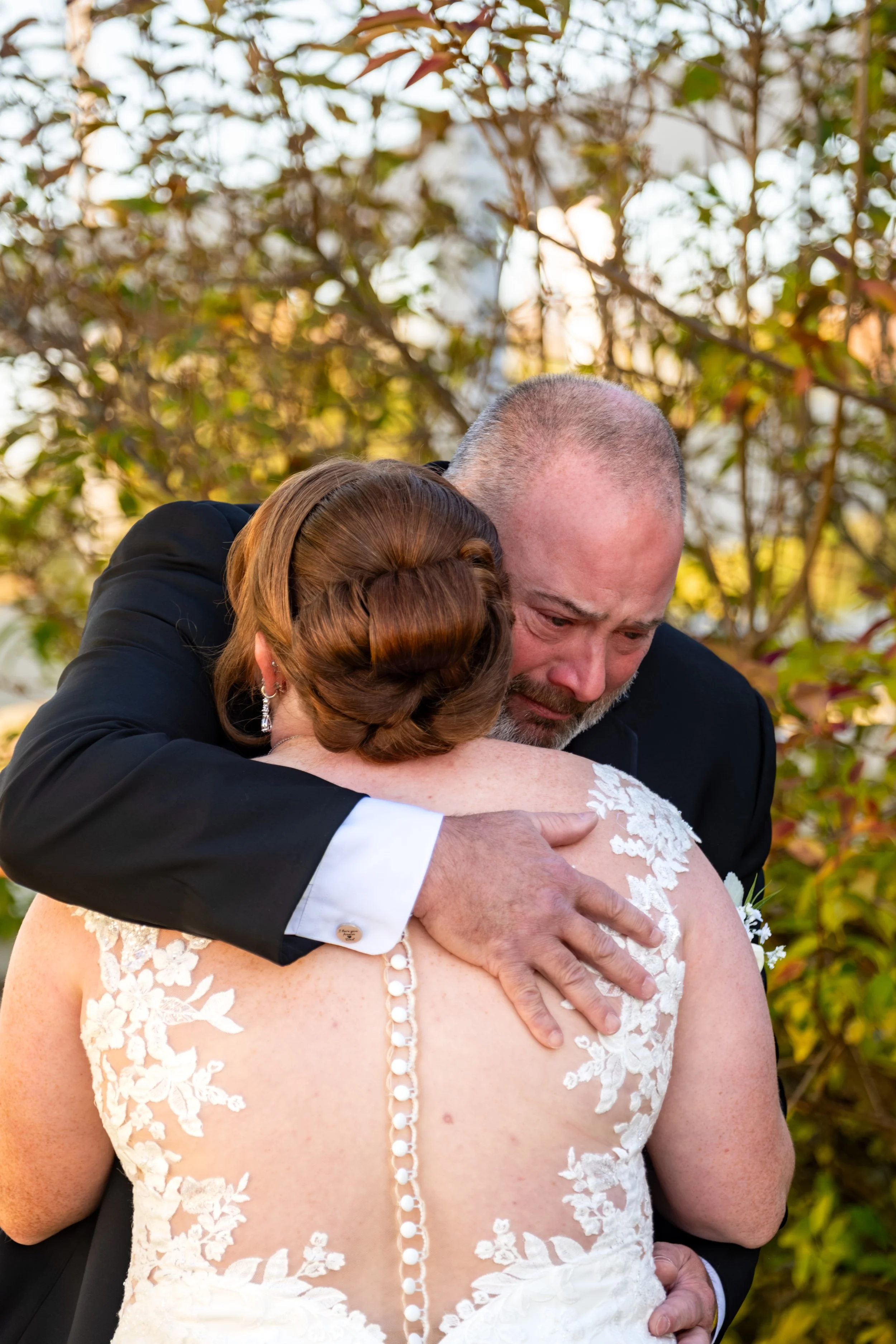 Erika and her dad in a tight hug surrounded by fall leaves at the Maine Wedding Barn and Event Center in Minot Maine fall wedding photography VMG Productions
