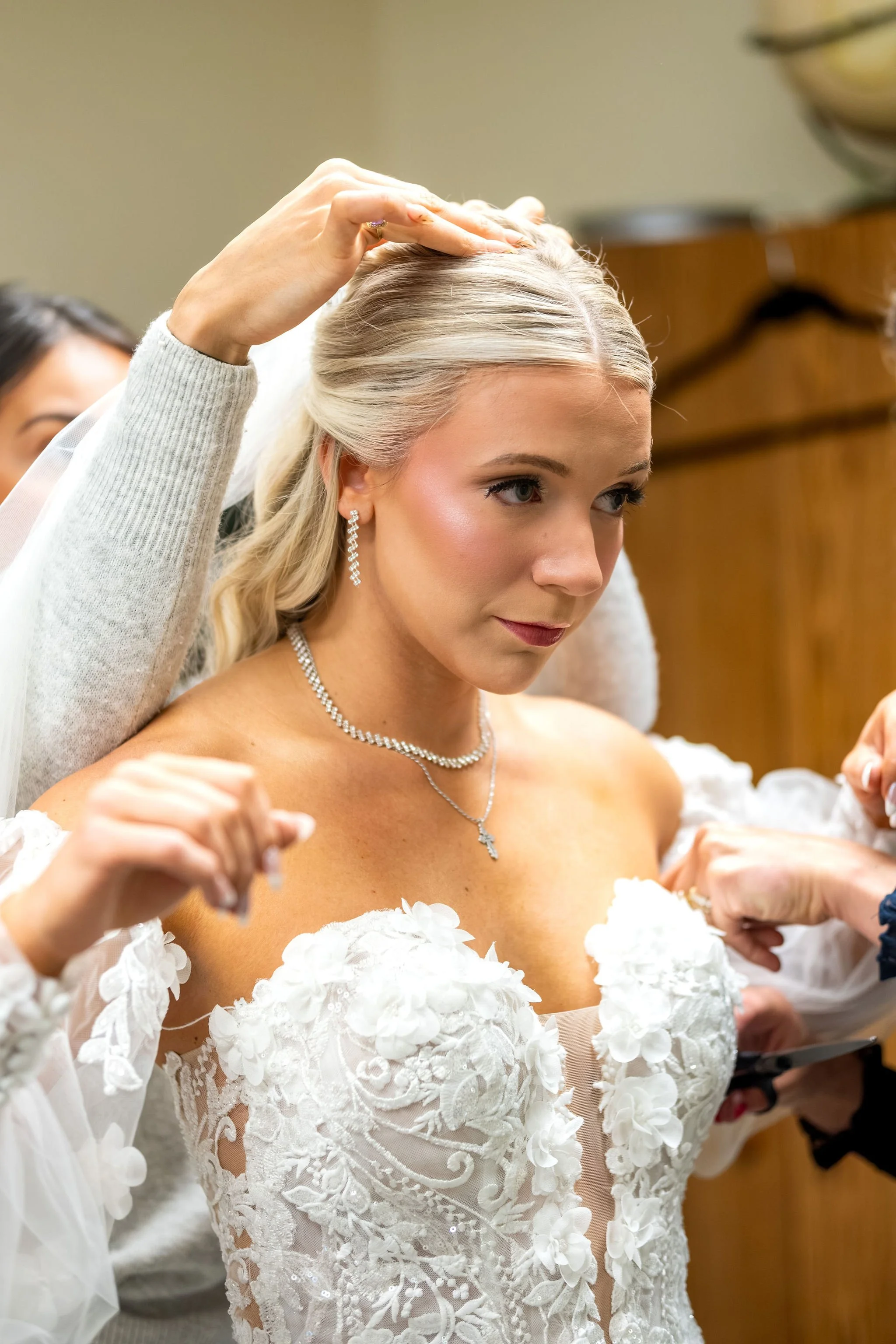 Jeremiah and Vienna bride surrounded by helping hands while veil and gown are adjusted at Holy Trinity Greek Orthodox Church Portland Maine spring wedding photography VMG Productions
