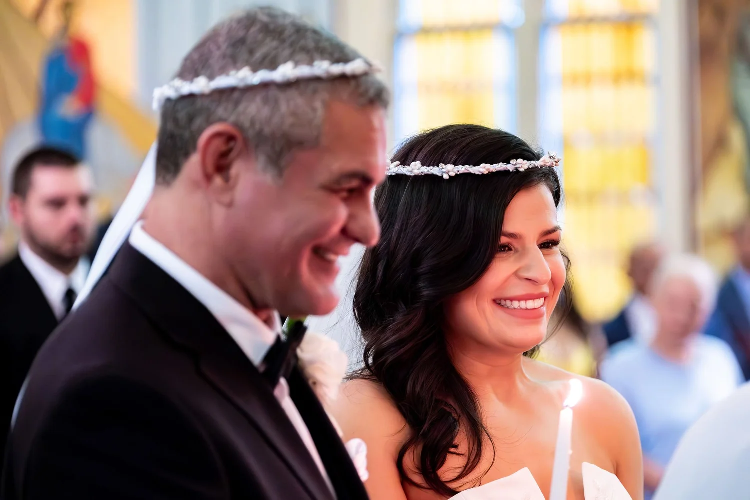 Nicole and Alexey laughing together in their stefana crowns at Holy Trinity Greek Orthodox Church Portland Maine summer wedding photography VMG Productions