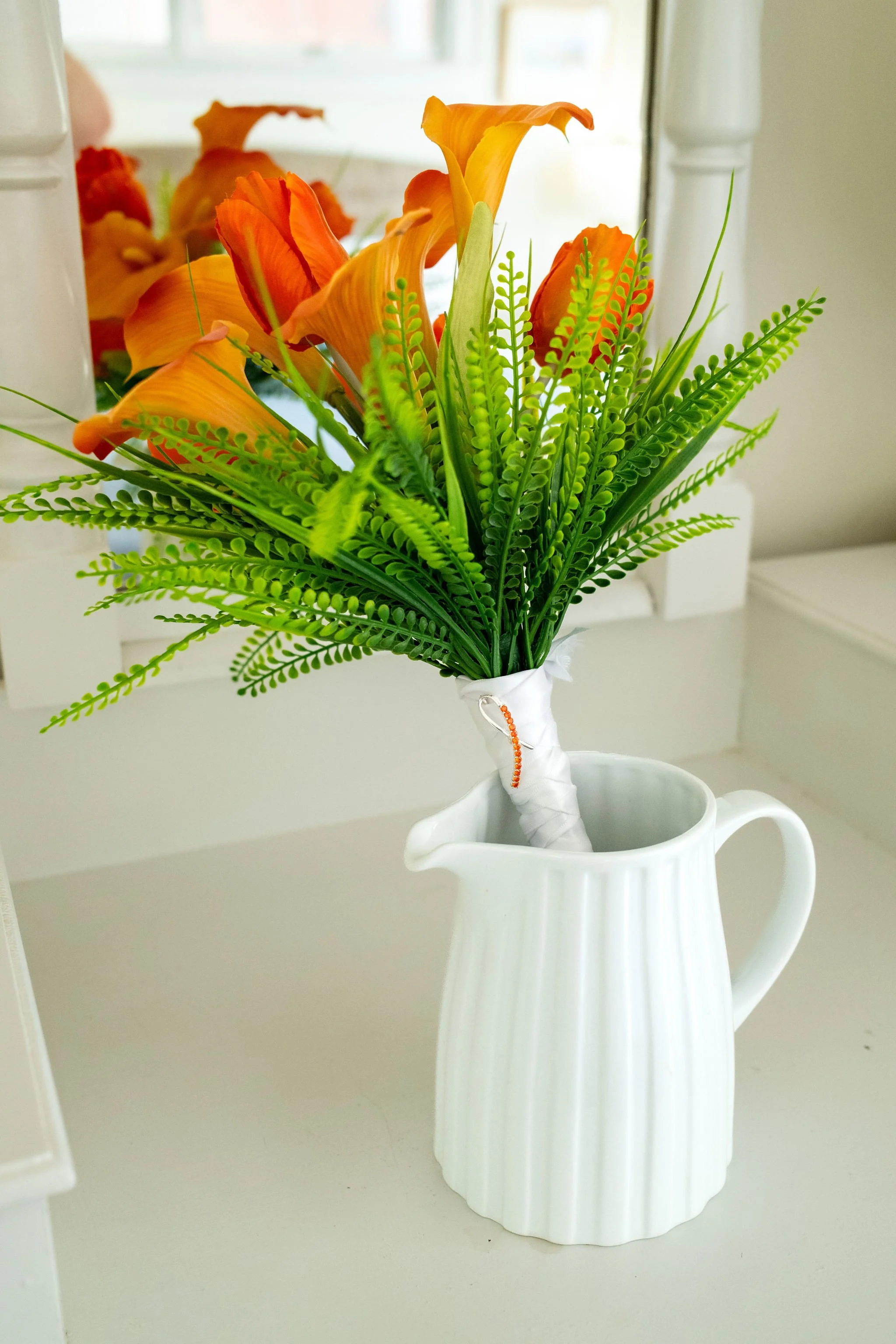 Orange calla lilies in a white pitcher as a wedding detail at a Mount Desert Maine private residence spring wedding photography VMG Productions