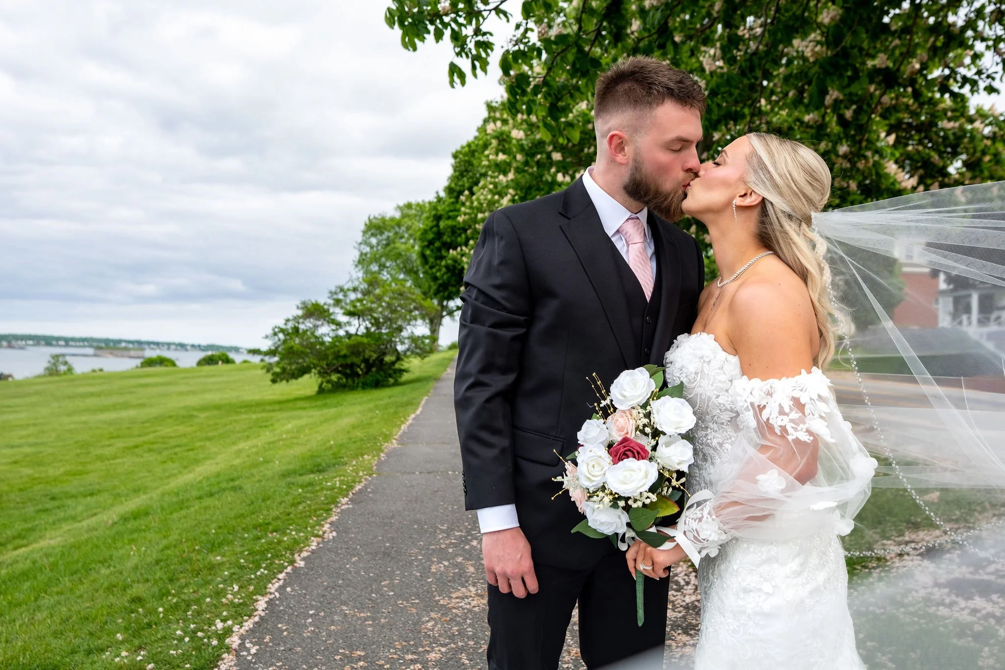 Jeremiah and Vienna bride looks down softly toward bouquet in intimate close-up portrait at Eastern Promenade Portland Maine spring wedding photography VMG Productions