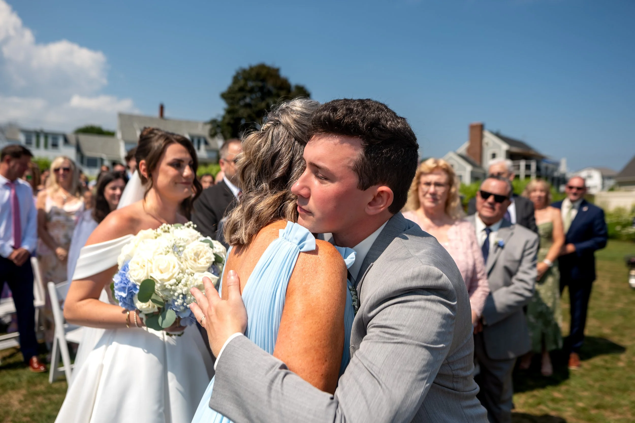 Anthony Pirolli hugging his mother at the aisle as Caroline watches from behind at Union Bluff Hotel in York Maine wedding photography VMG Productions