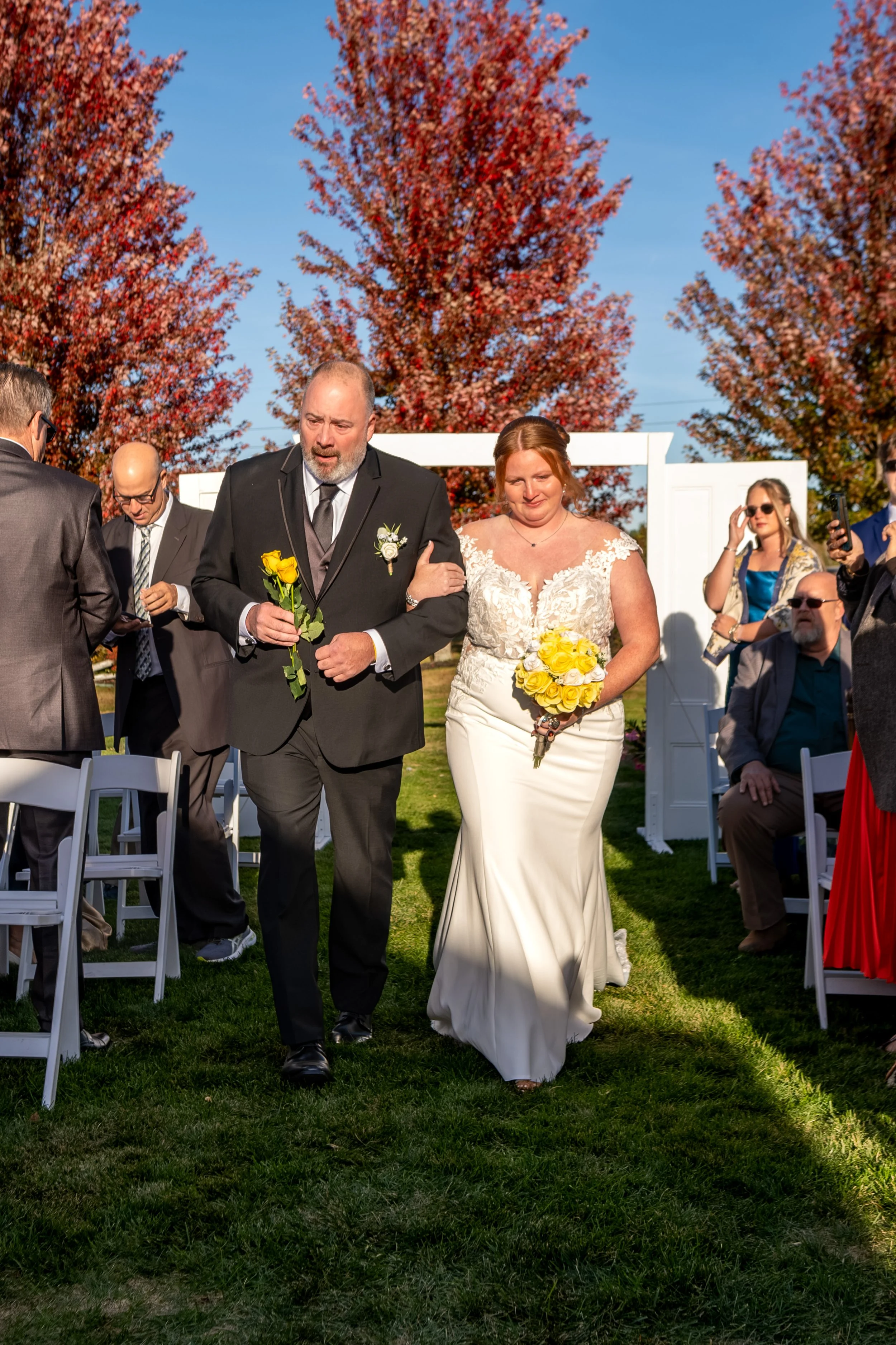 Erika and her dad walking the aisle past guests on both sides at the Maine Wedding Barn and Event Center in Minot Maine fall wedding photography VMG Productions