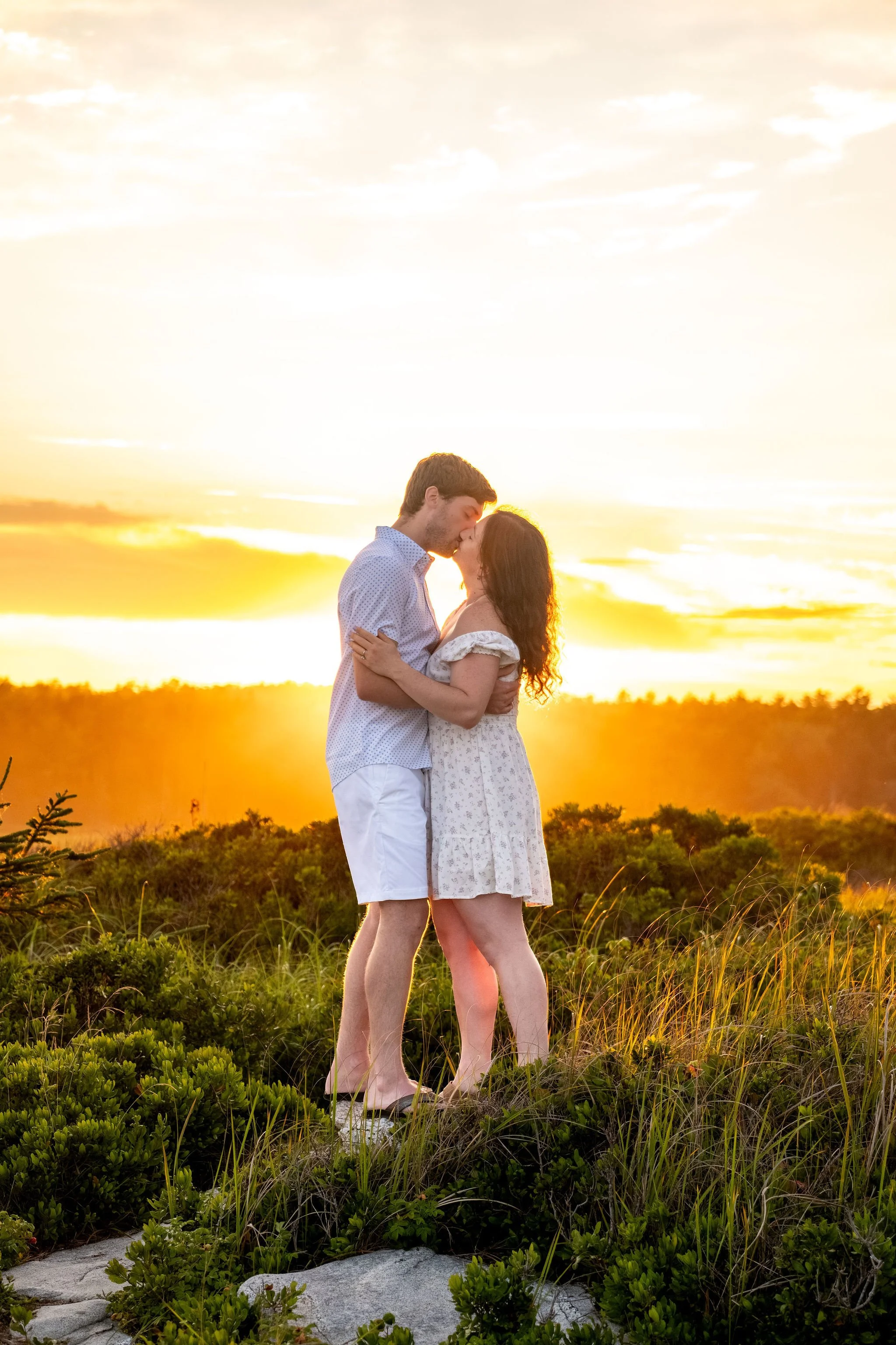 Kirstie and Lucas kissing in the golden haze with the sun setting over the marsh at Reid State Park in Georgetown Maine engagement photography VMG Productions