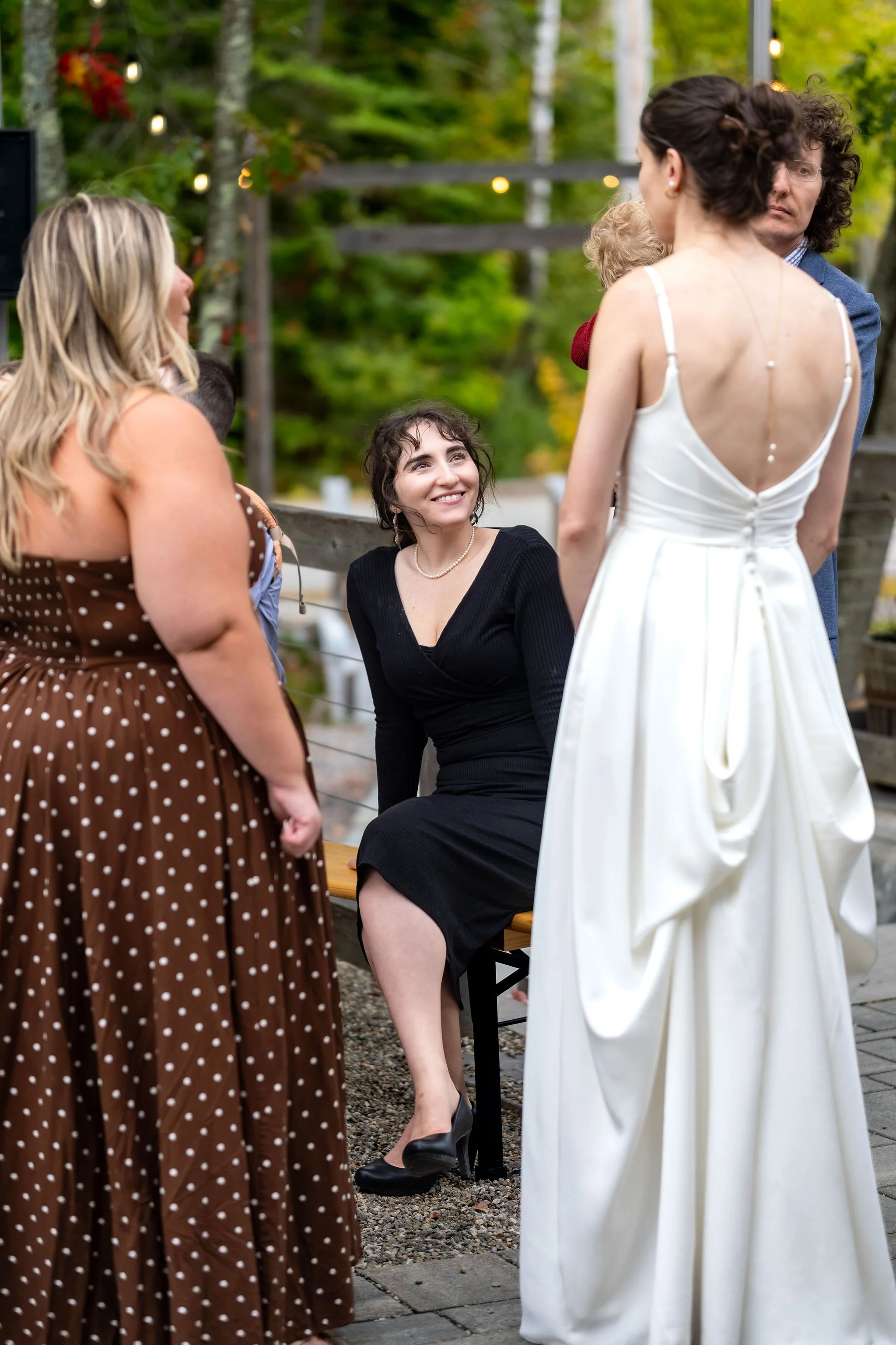 A guest smiling up at Victoria during cocktail hour with the pearl strand down her back at The Cellars at Allagash Brewing Company in Portland Maine fall wedding photography VMG Productions