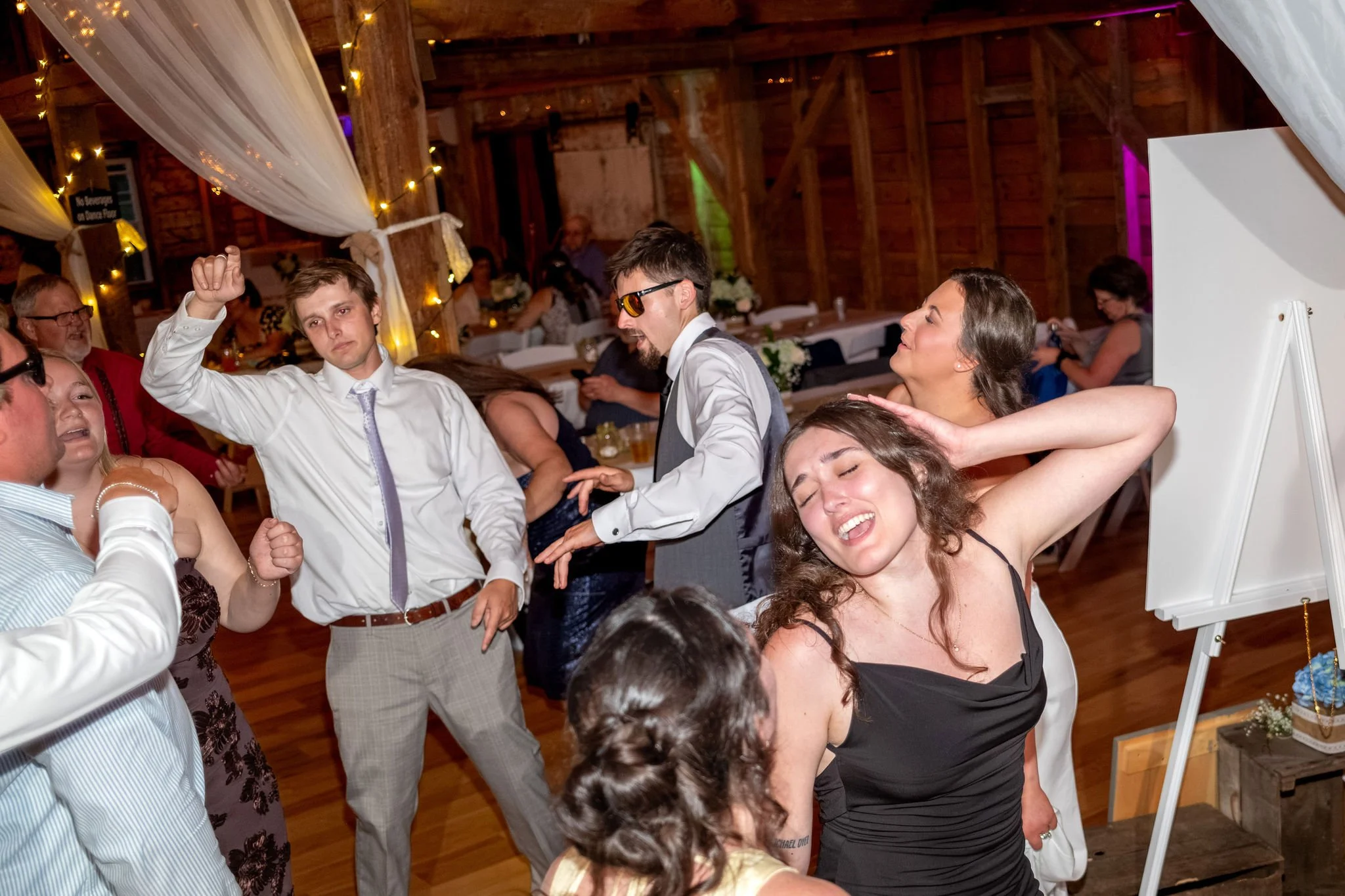 Alyssa and Colby guests dancing under string lights during the reception at the 1888 Barn Bethel Maine summer wedding photography VMG Productions