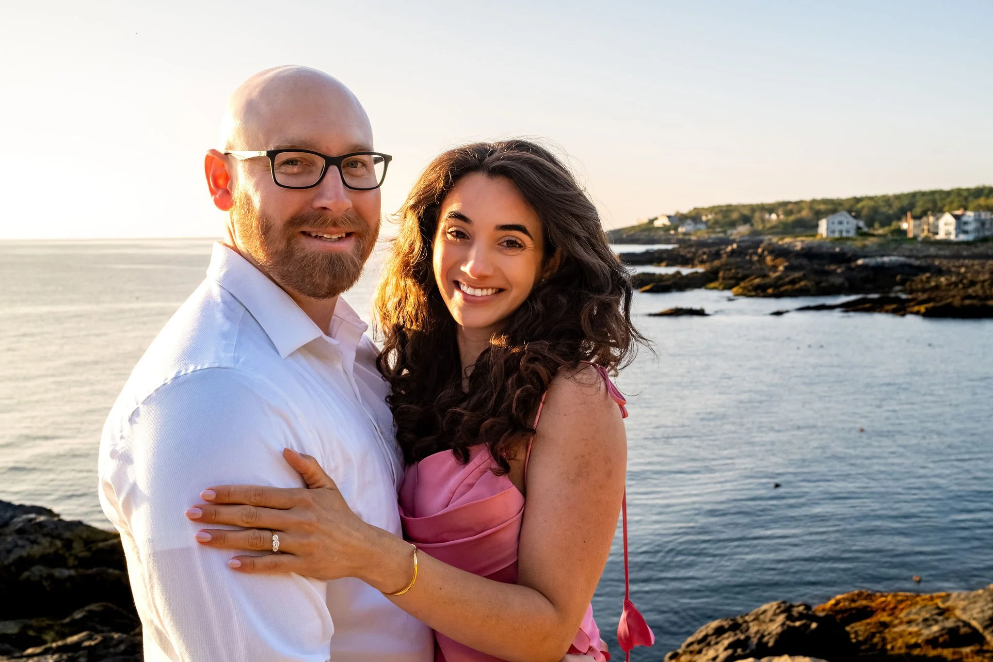 Zack and Helena smiling at the camera with the rocky coastline and ocean behind them on Marginal Way in Ogunquit Maine sunrise proposal and engagement photography VMG Productions