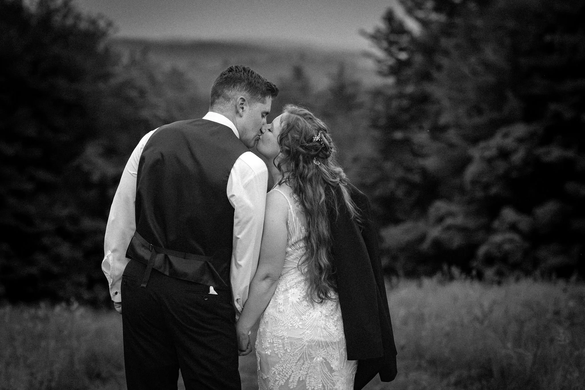 Kayla and Ethan DeAngelis black and white portrait kissing in the summer field at dusk at their Sanbornton New Hampshire wedding photography VMG Productions
