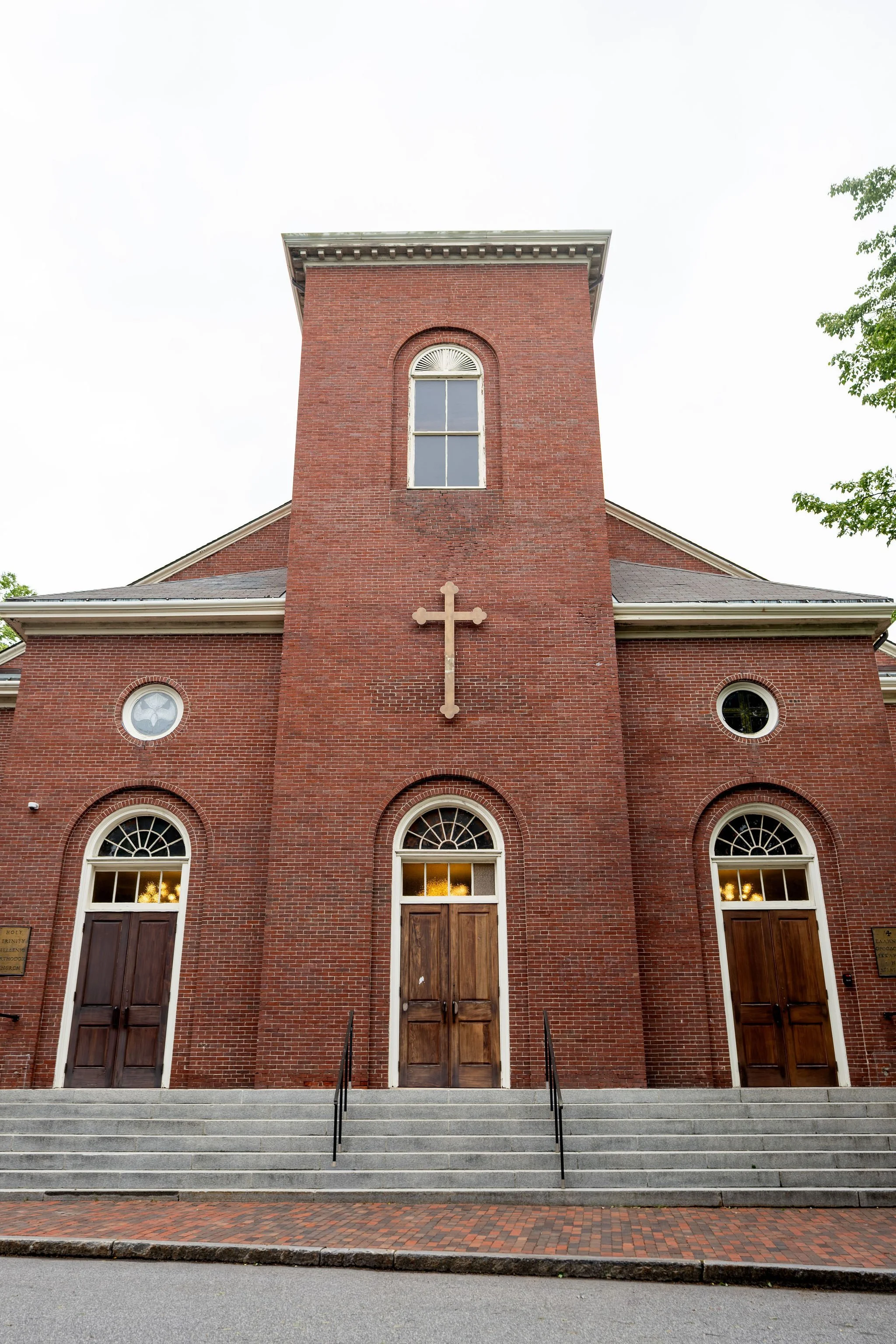 Jeremiah and Vienna symmetrical exterior view of church facade before ceremony begins at Holy Trinity Greek Orthodox Church Portland Maine spring wedding photography VMG Productions
