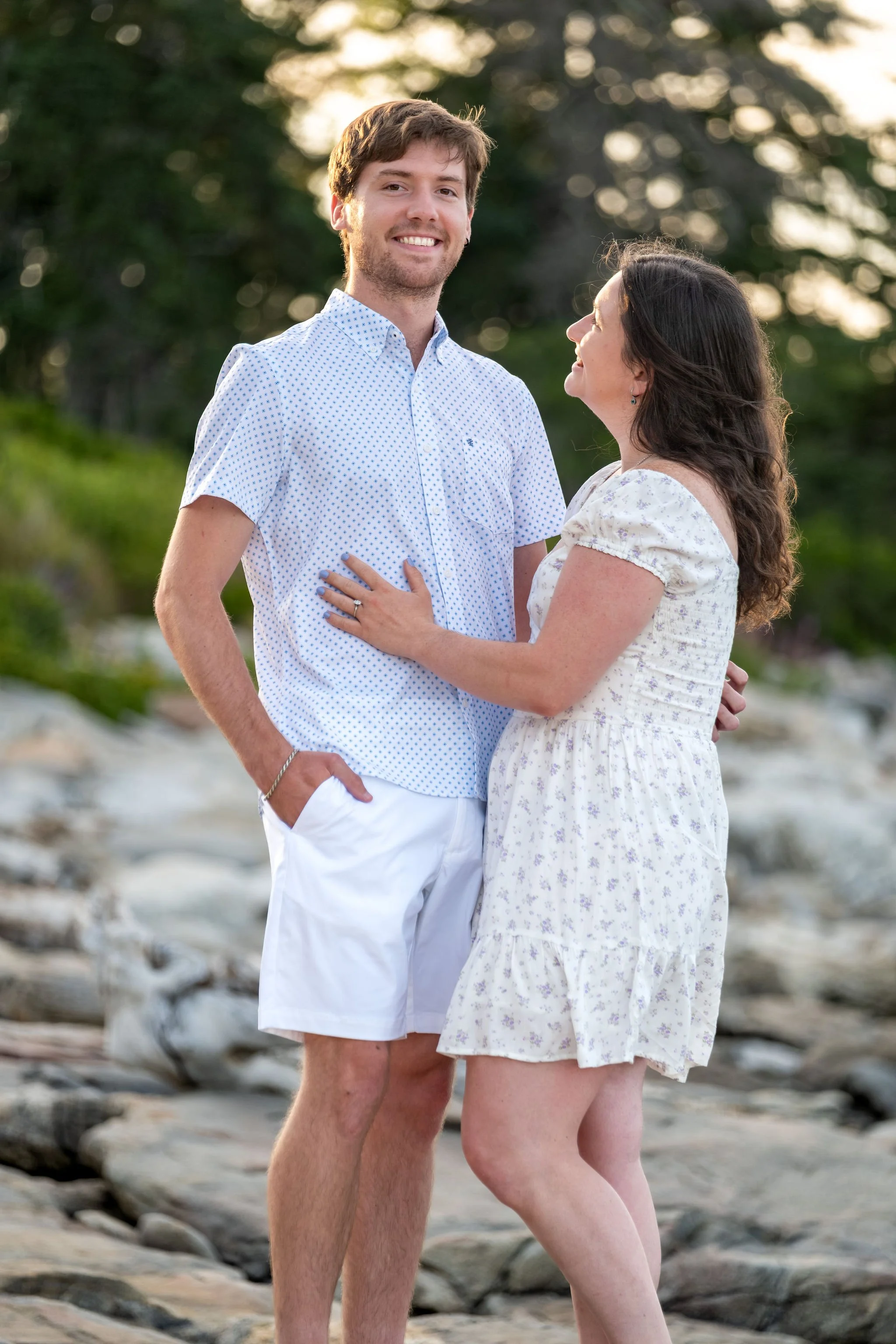Kirstie looking up at Lucas on the granite ledges at Reid State Park in Georgetown Maine engagement photography VMG Productions