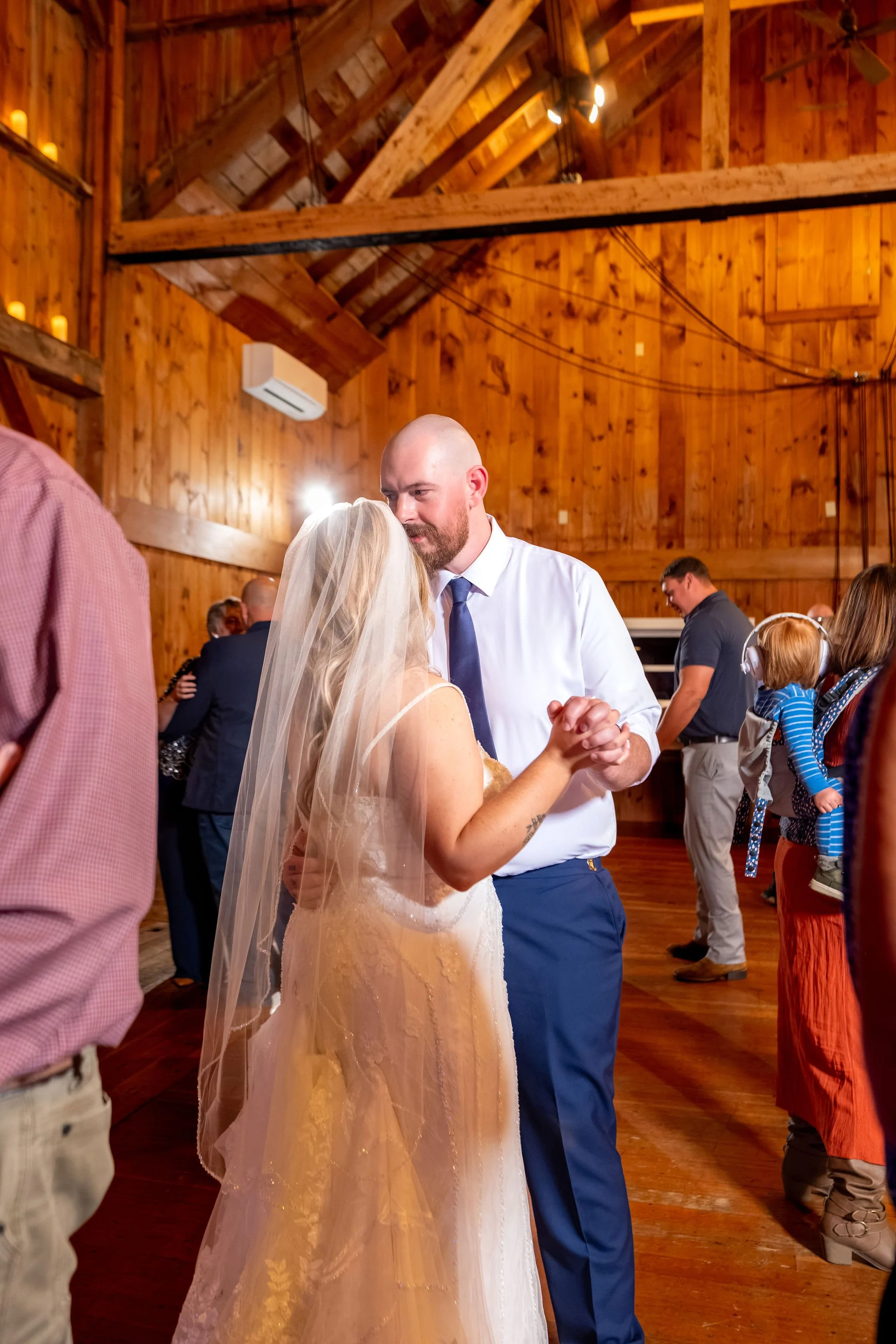 Sam and Ellie dancing close on the floor with guests dancing behind them at Boothbay Playhouse in Boothbay Maine fall wedding photography VMG Productions