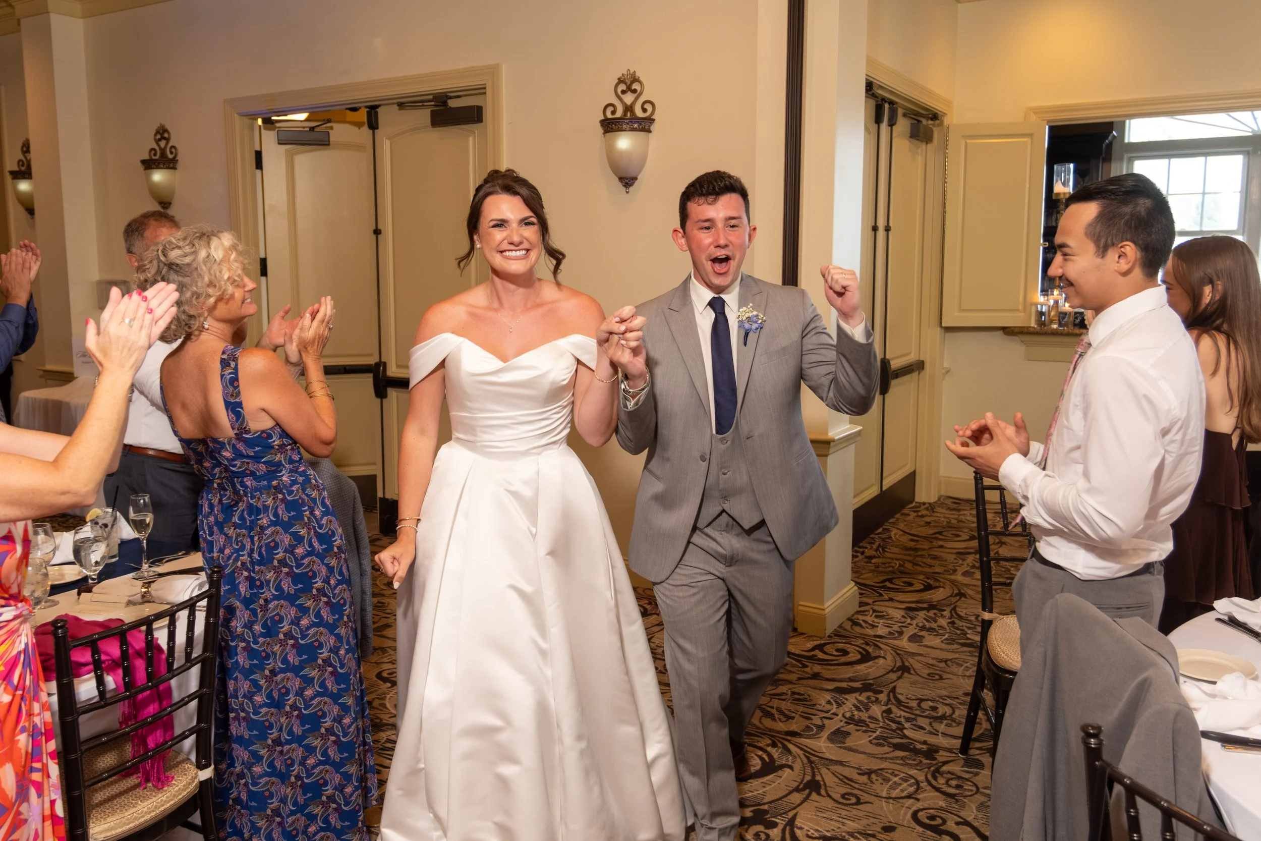 Caroline and Anthony Pirolli entering the reception hand in hand as guests stand and applaud at Union Bluff Hotel in York Maine wedding photography VMG Productions