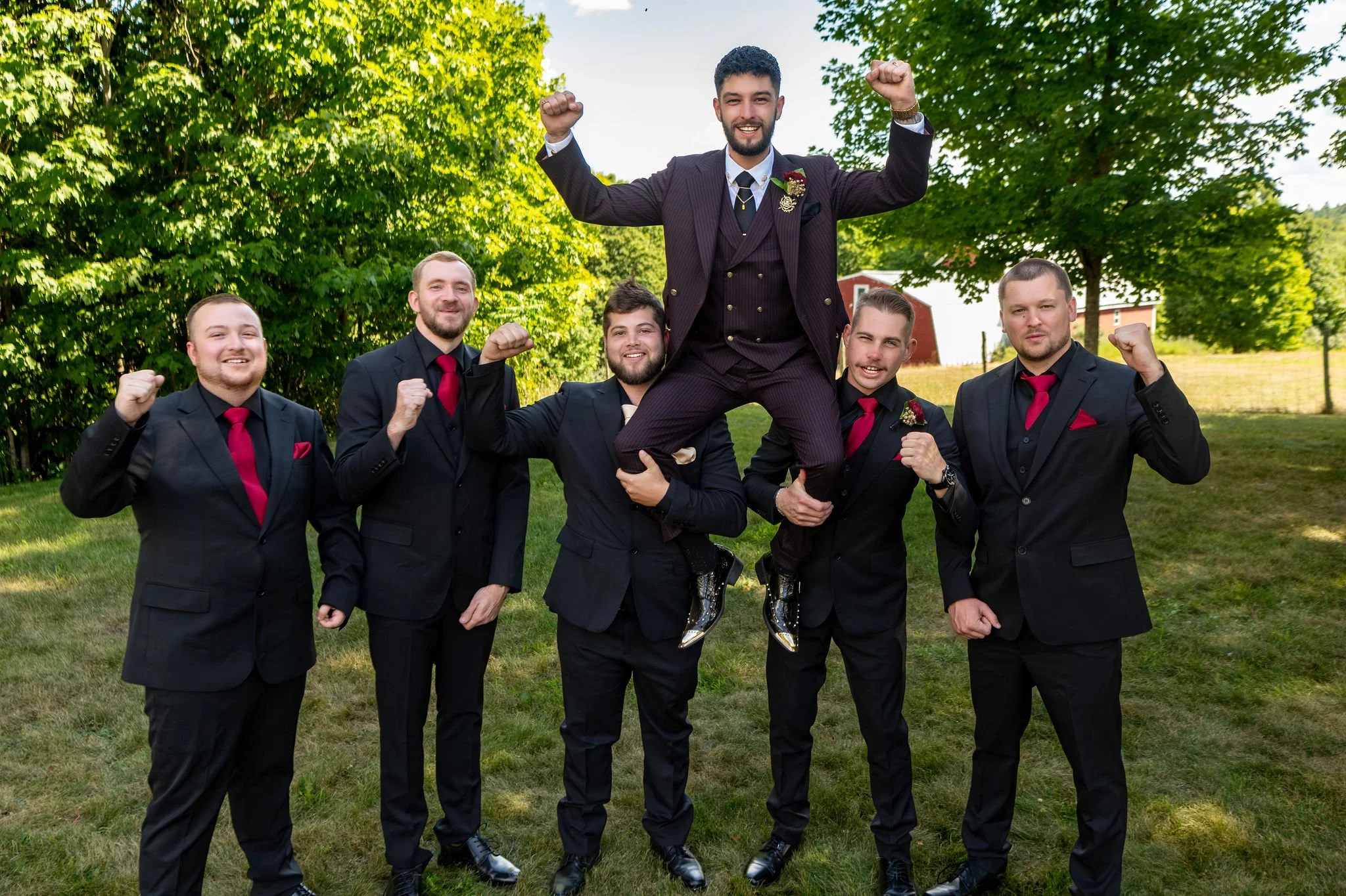 Chase Begin lifted onto his groomsmen's shoulders on the lawn at Maple Hill Farm Inn and Conference Center in Hallowell Maine summer wedding photography VMG Productions