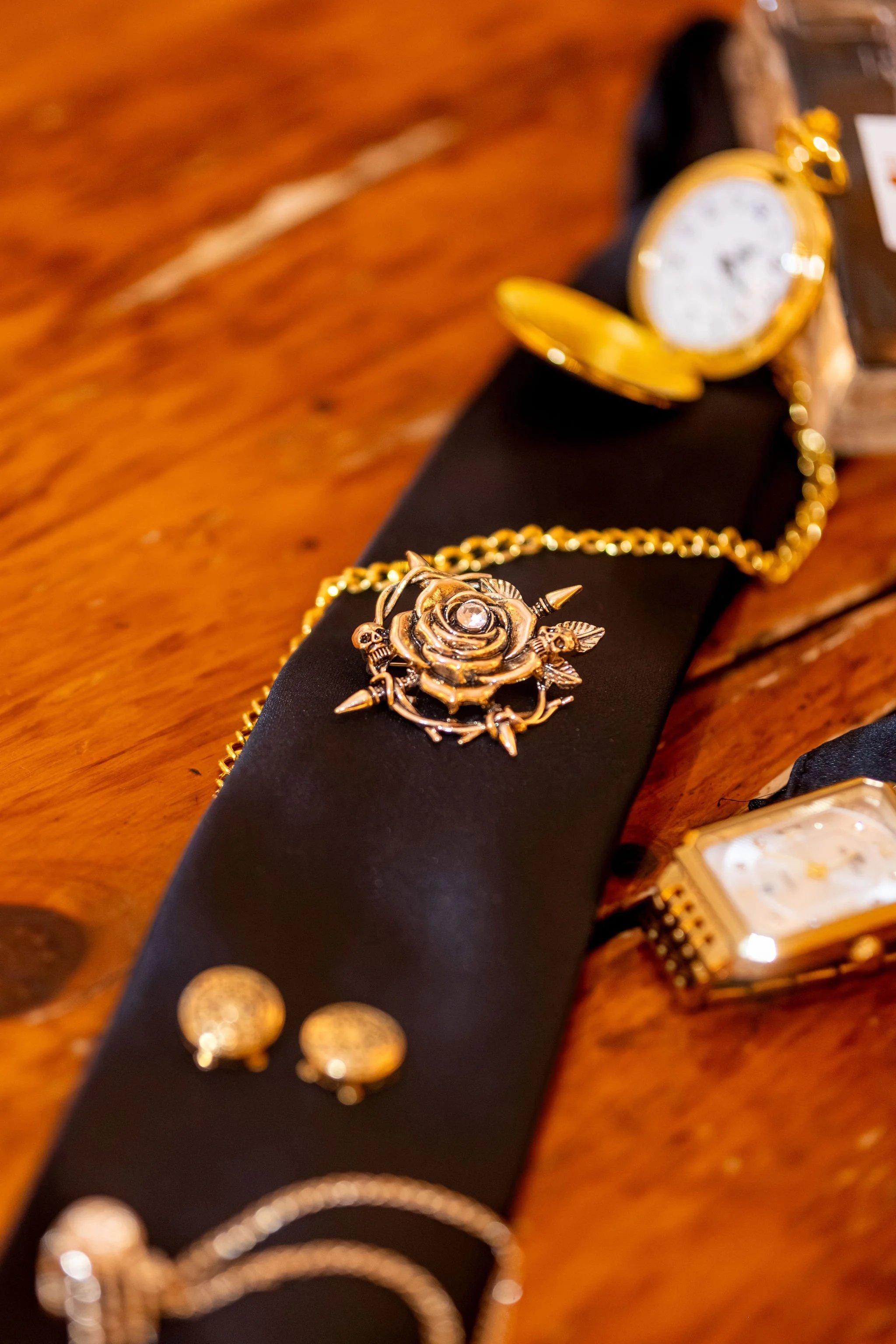 Chase Begin's gold pocket watch cufflinks and rose pin laid out on a wooden table at Maple Hill Farm Inn and Conference Center in Hallowell Maine summer wedding photography VMG Productions